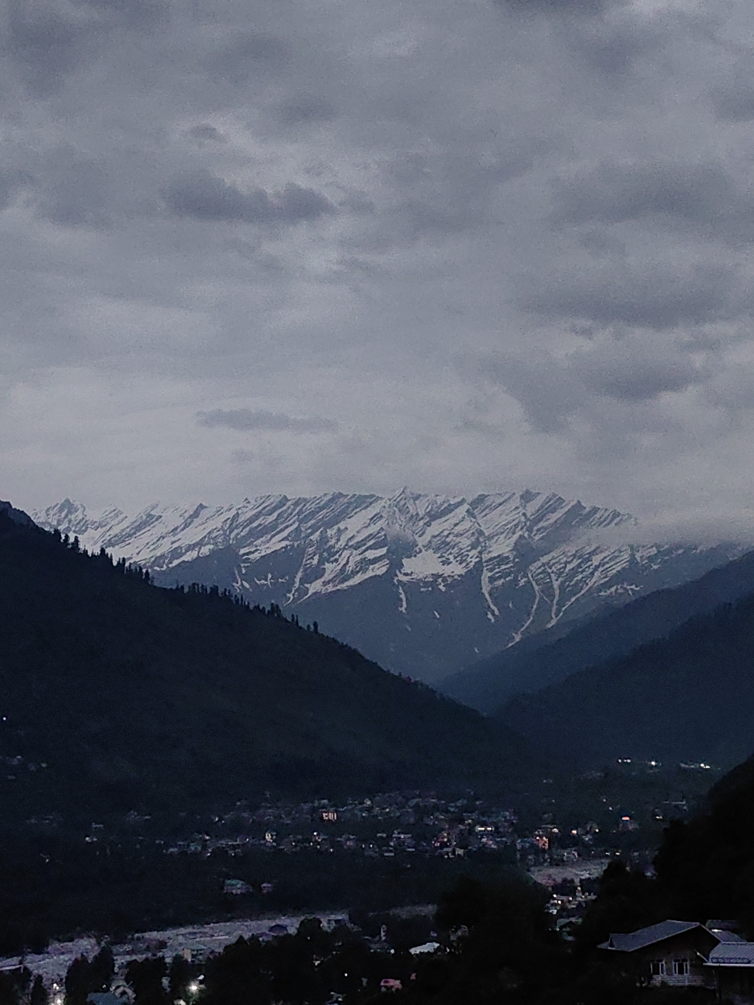 Vashisht village at dusk, Himalayas looming under heavy clouds