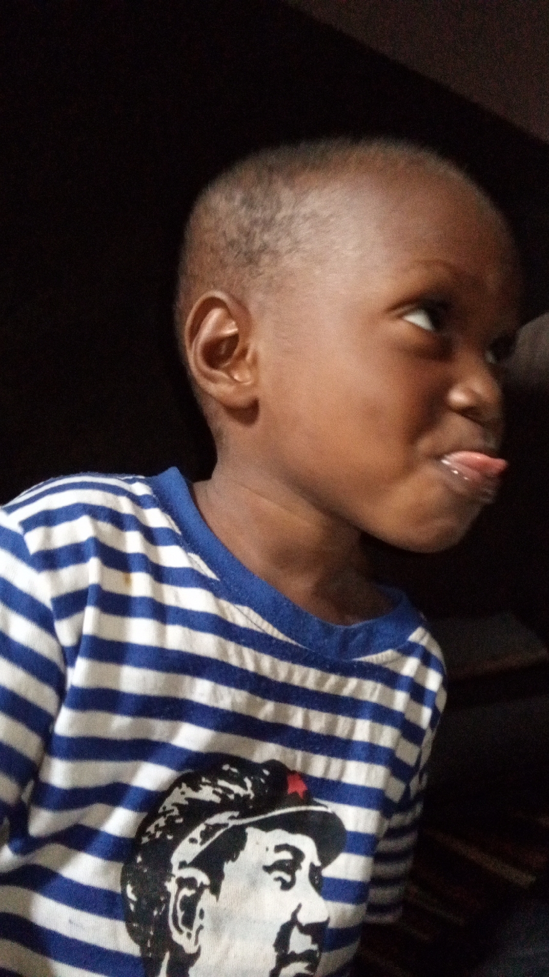 Child sticks tongue out in playful moment, Sabon Tasha