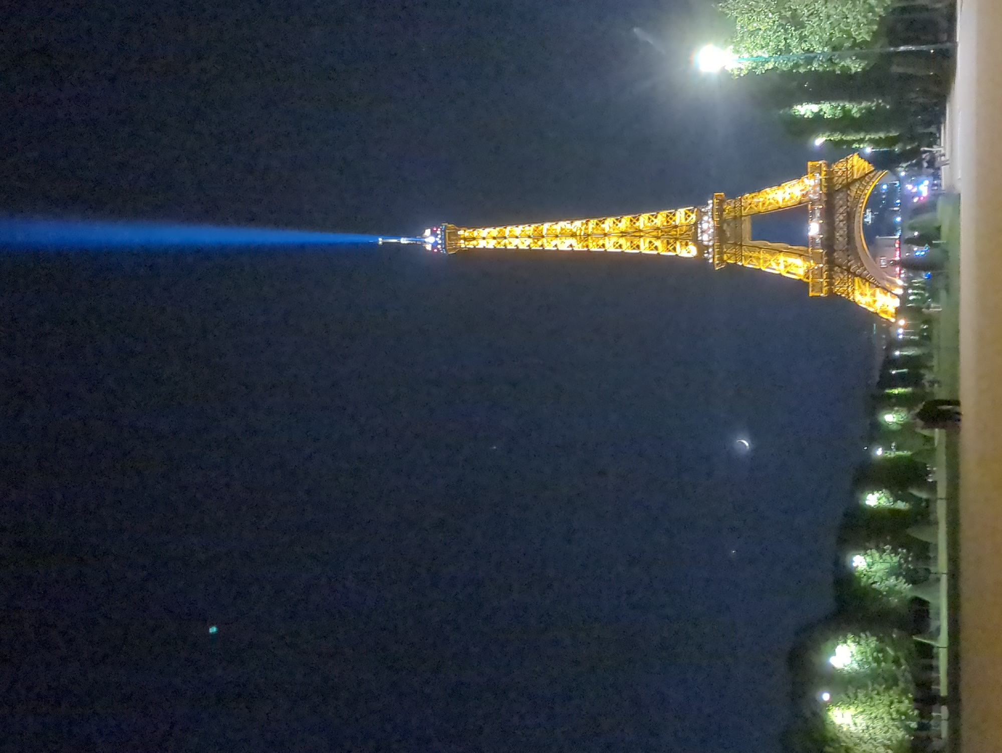 Blue light beam spotted extending from illuminated Eiffel Tower