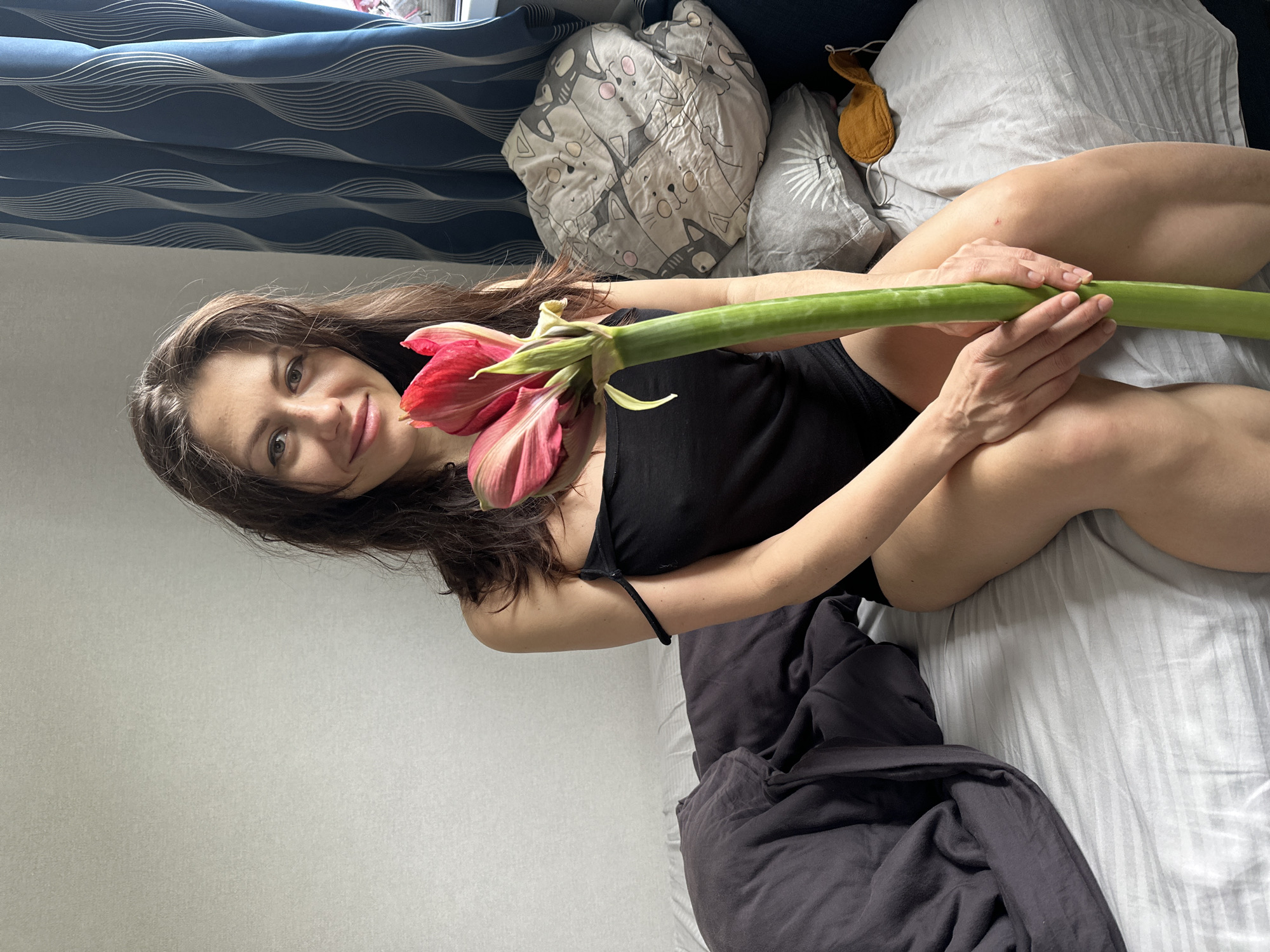 Woman poses with flower in bedroom photography session