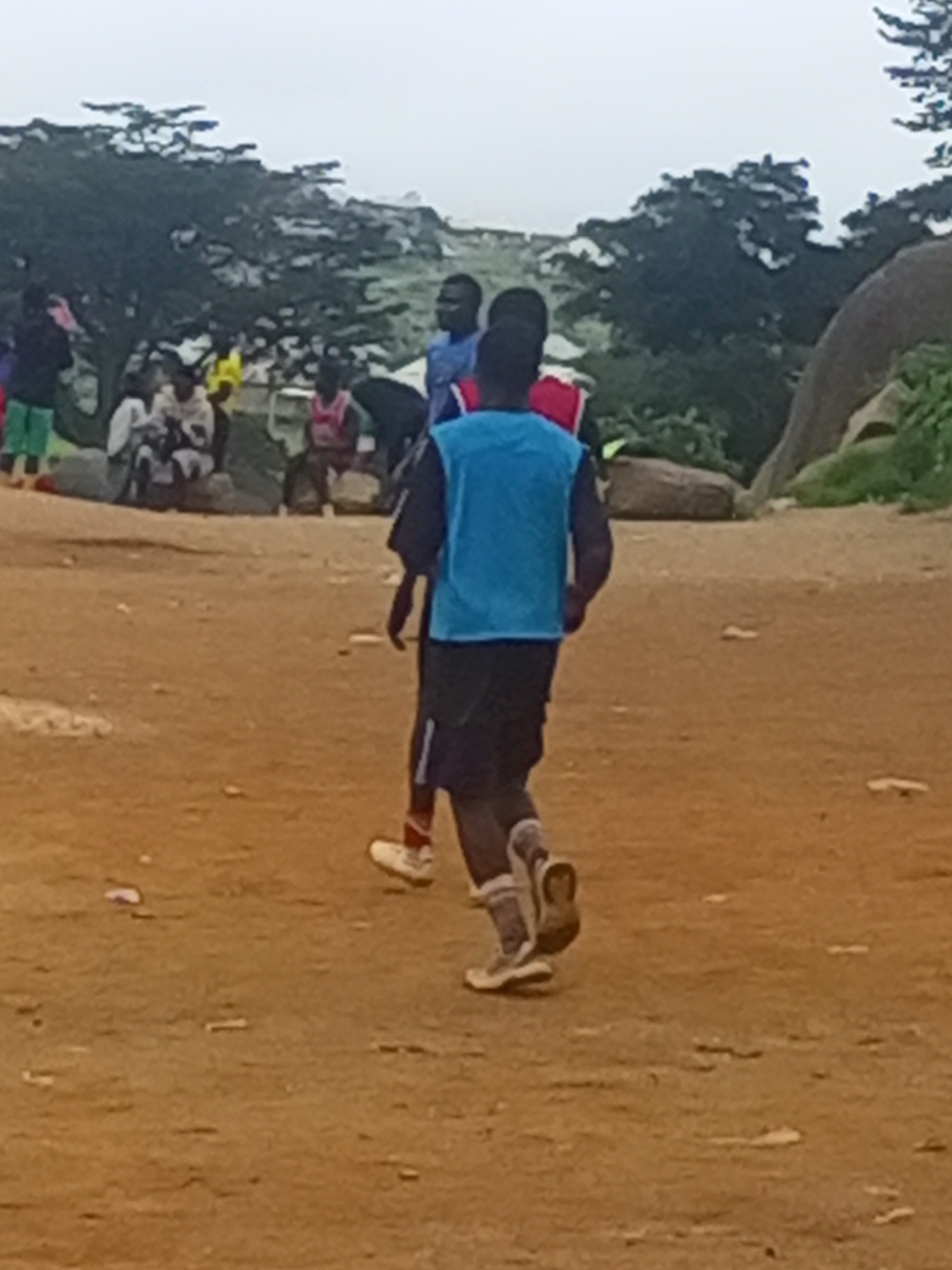 Football on a rocky Jos field under overcast skies
