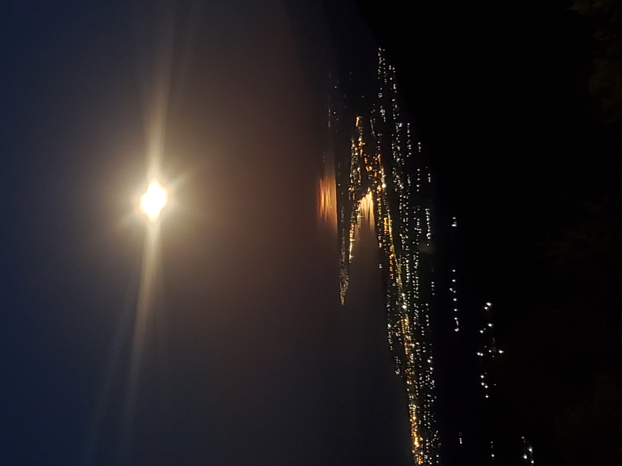 Moonlit coastal city photographed from above at dusk