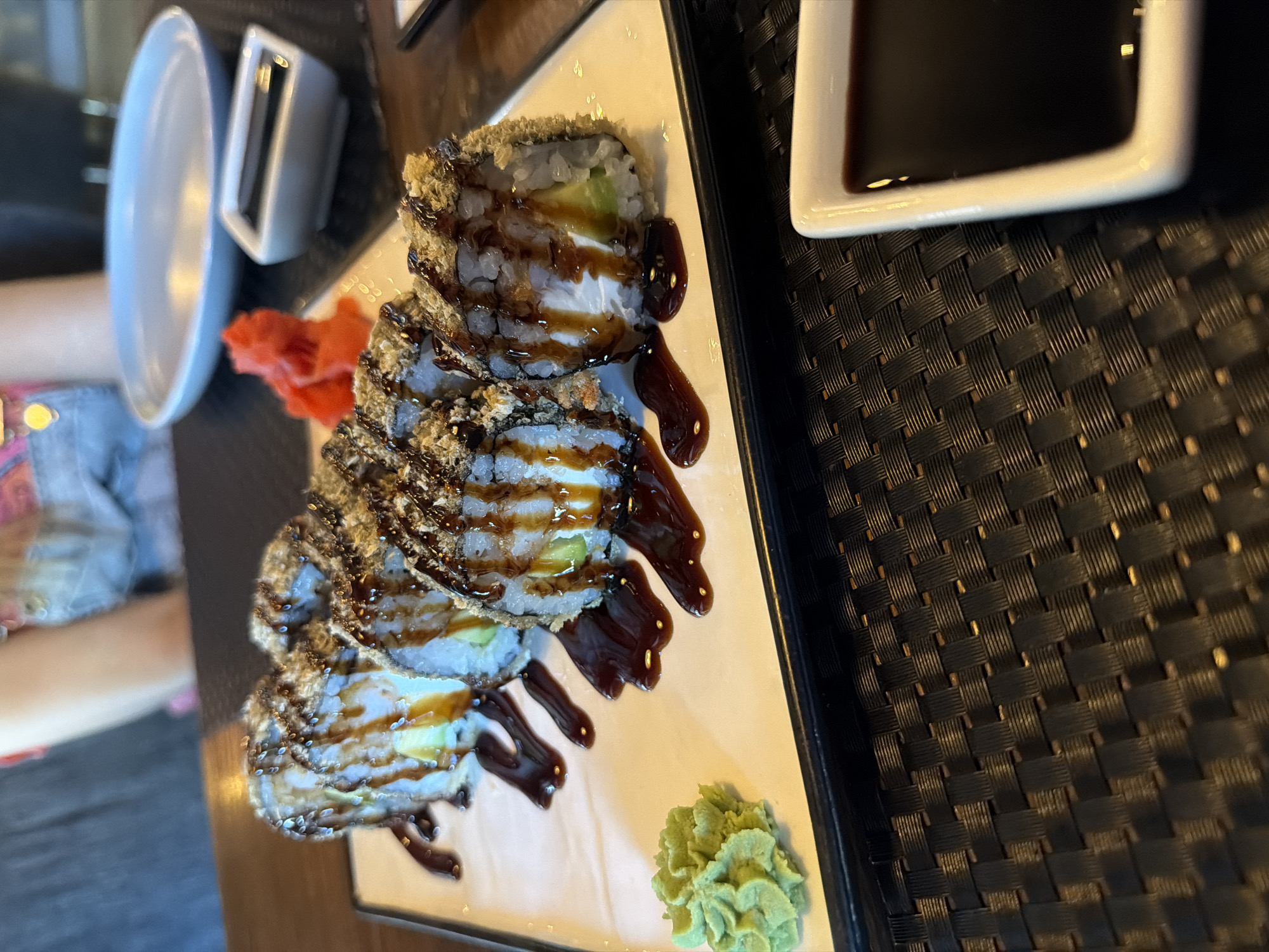 Deep-fried sushi rolls plated with wasabi and dark sauce