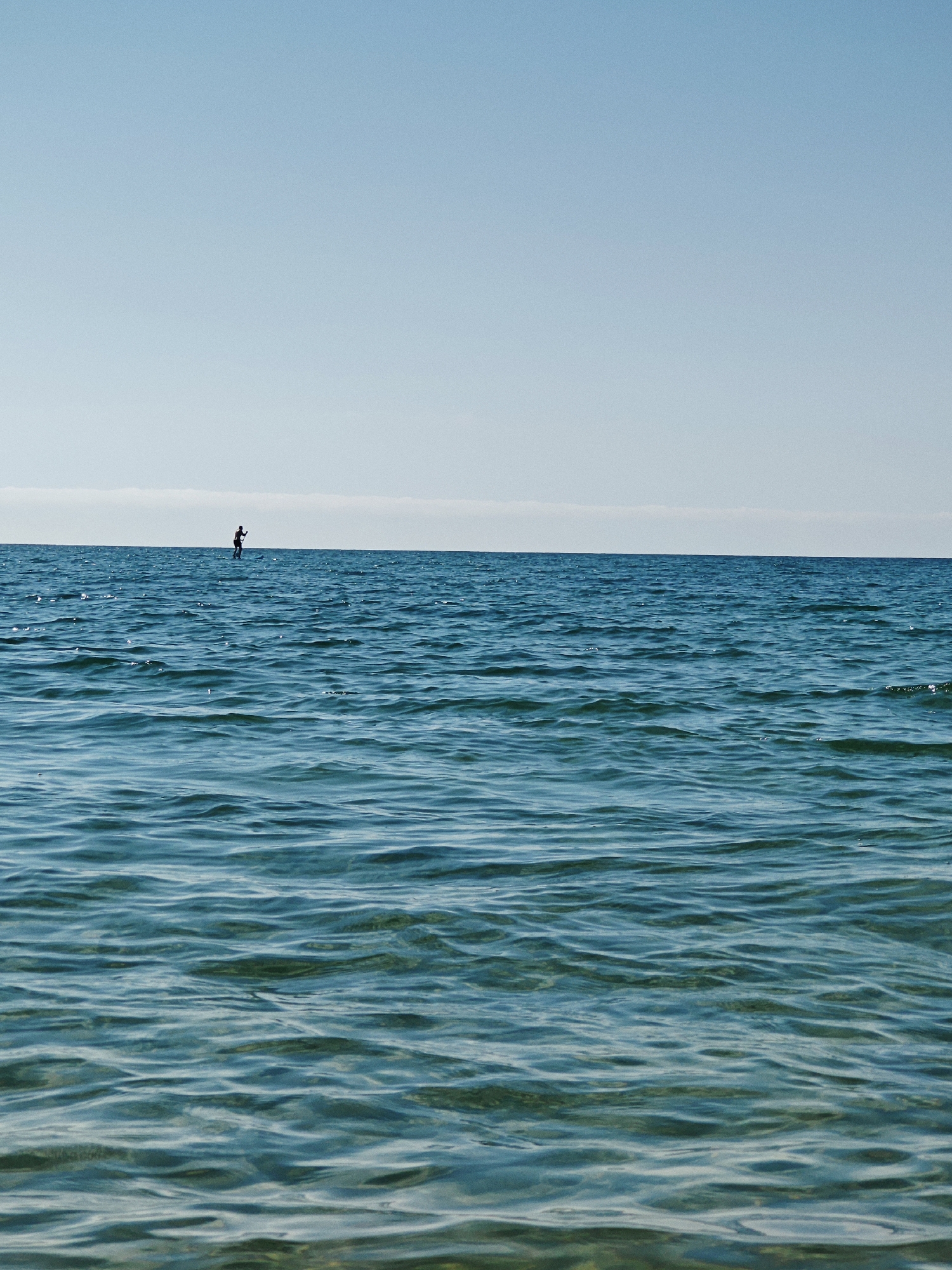 Clear morning on the ocean: paddleboarding, sailing, and swimming.