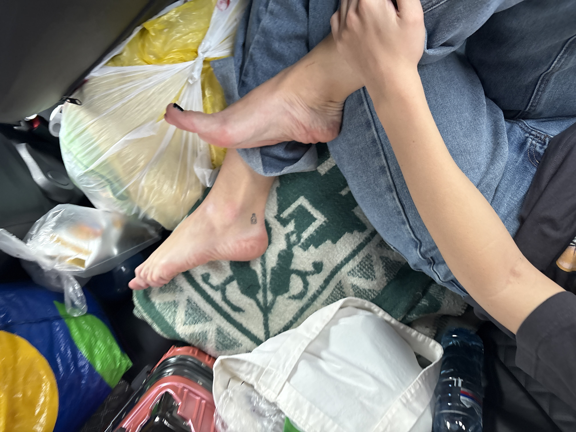 Person sits barefoot in cluttered vehicle cargo area, Sedanovo