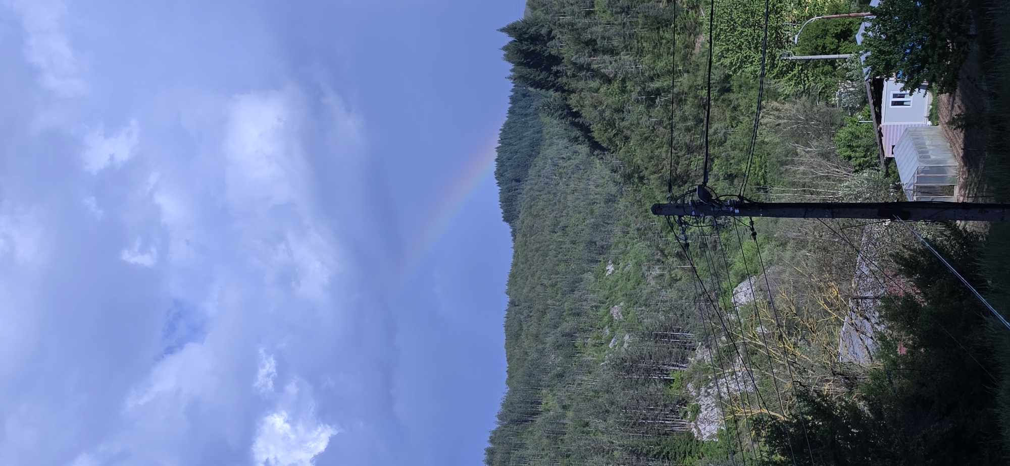 Rainbow appears over forested hills in Rudozem, Bulgaria