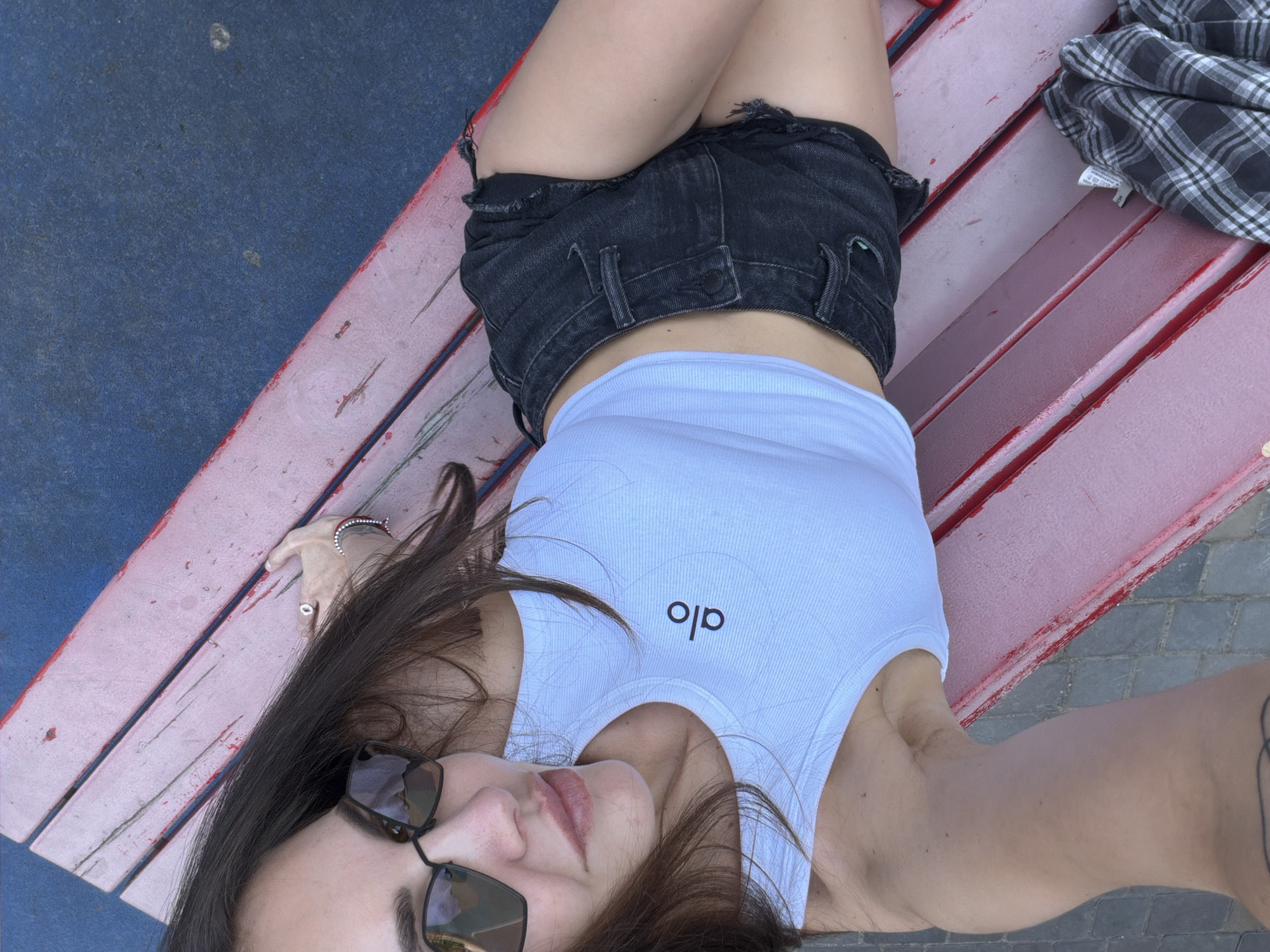 Woman rests on park bench with baby stroller nearby