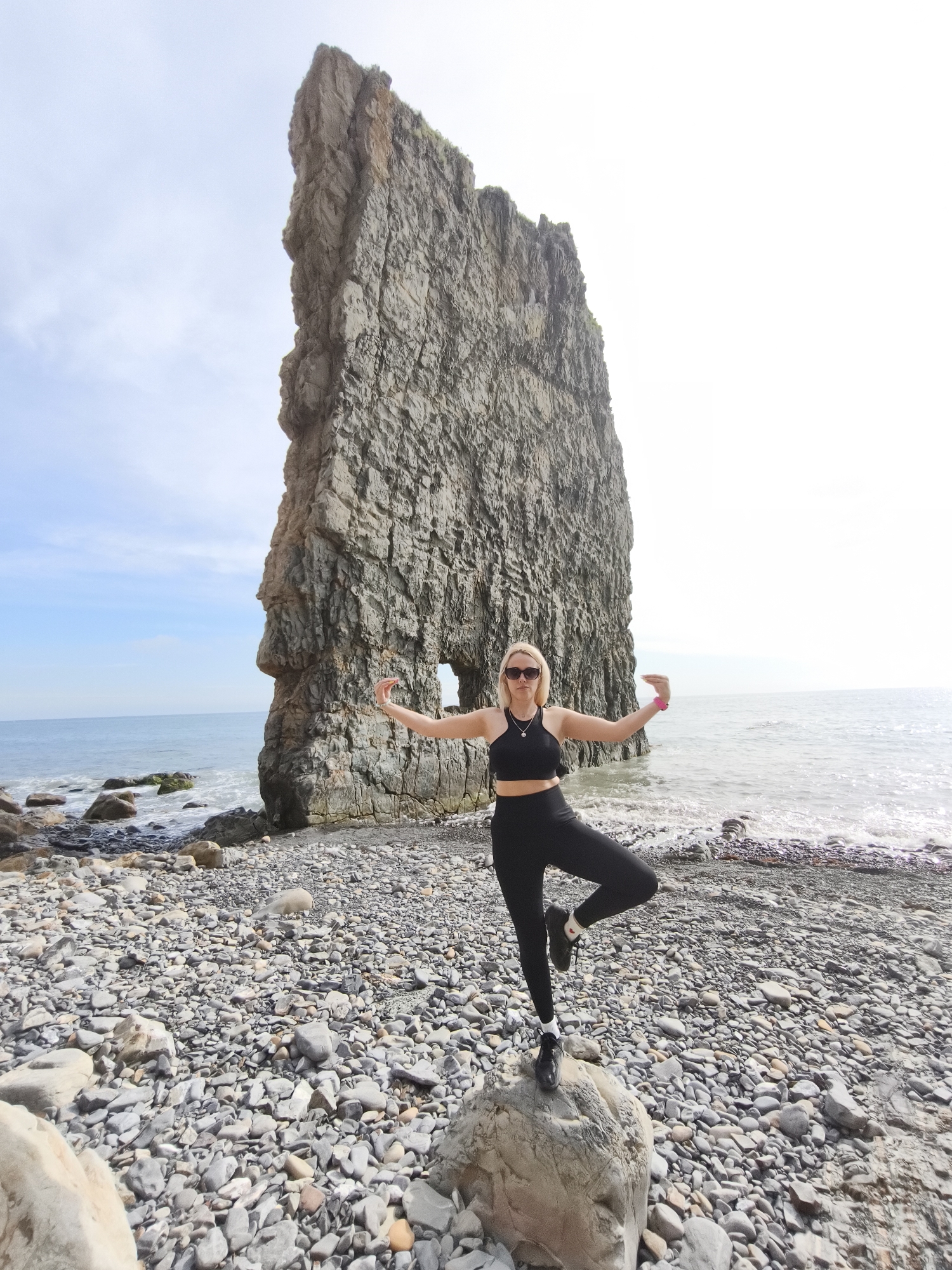 Woman practices yoga on rocky beach in Praskoveyevka, Russia