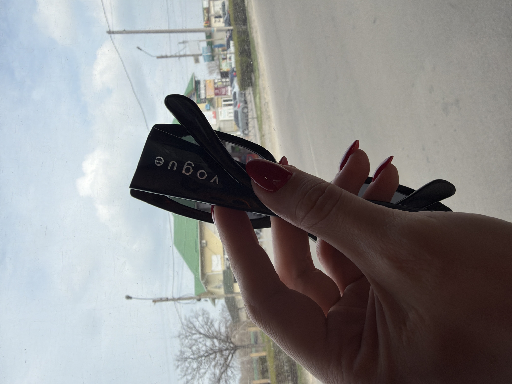 Person shows off Vogue sunglasses in Kamianske window