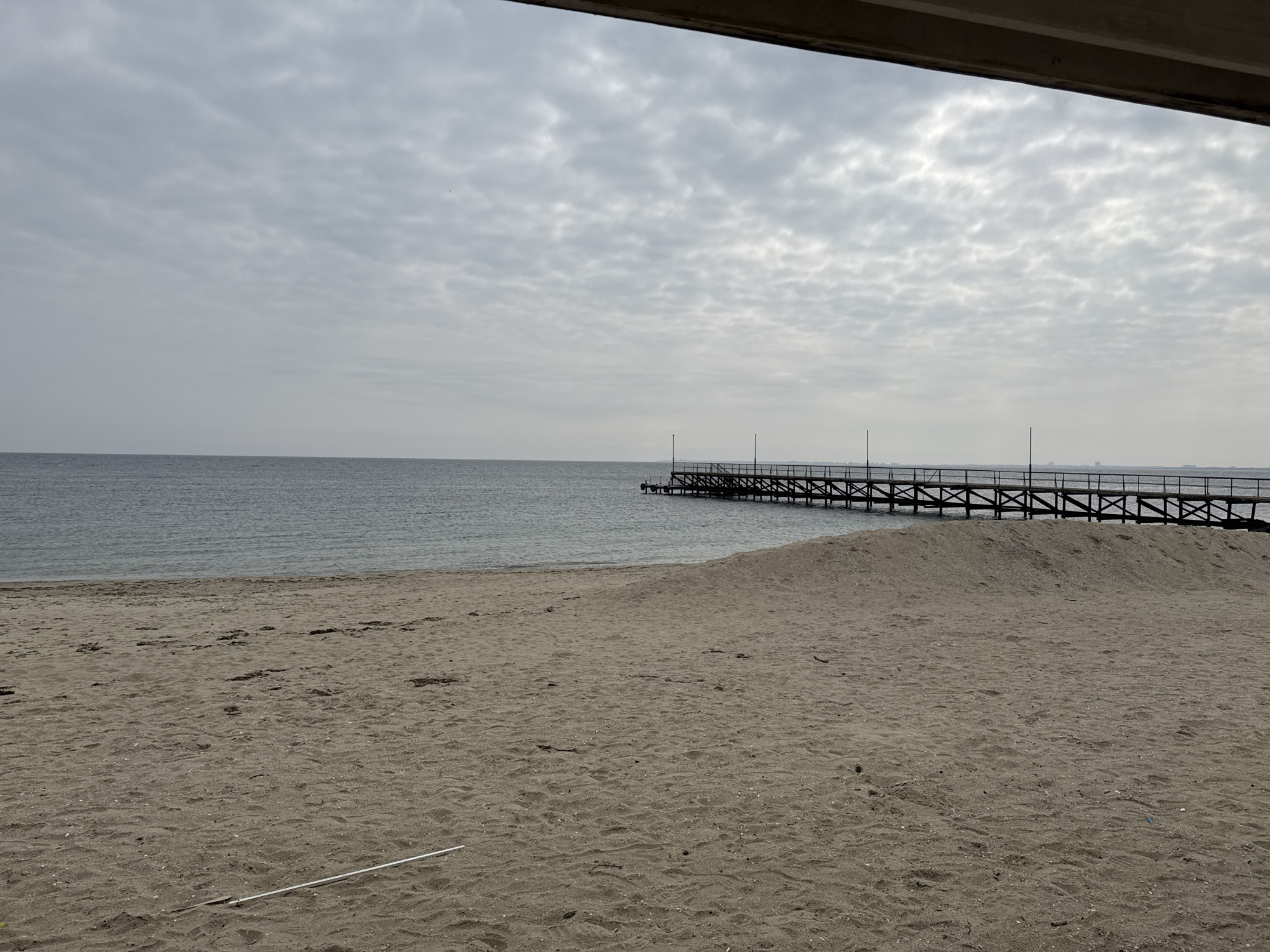 Overcast day at Ravda beach with wooden pier