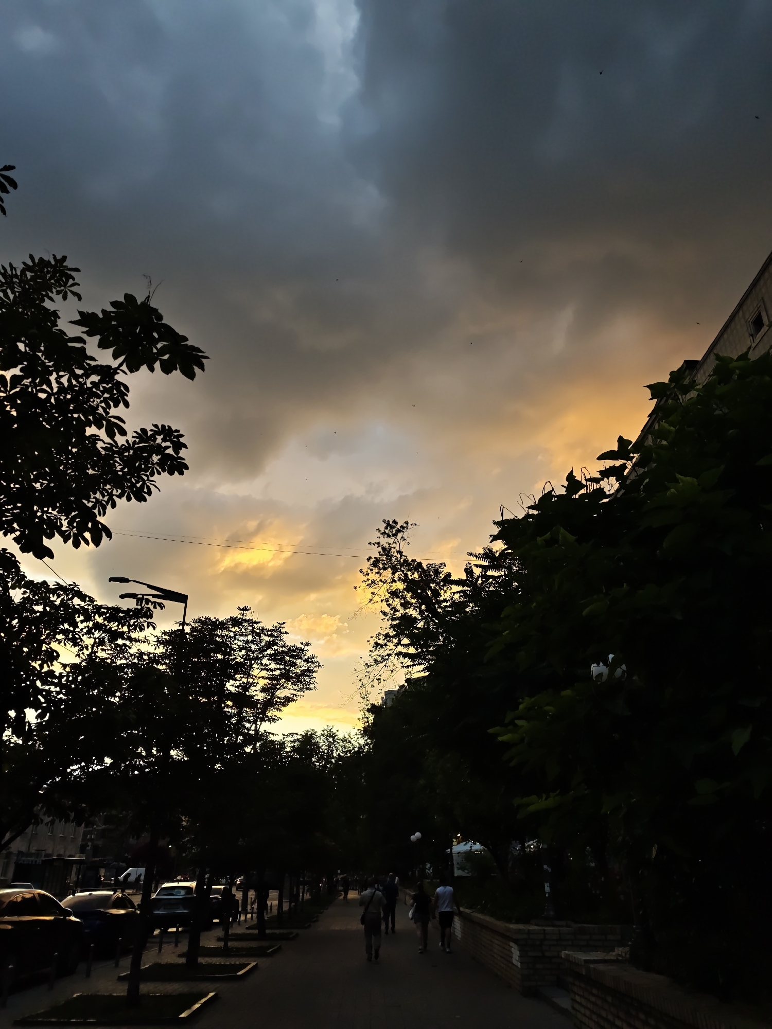 Storm clouds meet golden sunset over a Kyiv street