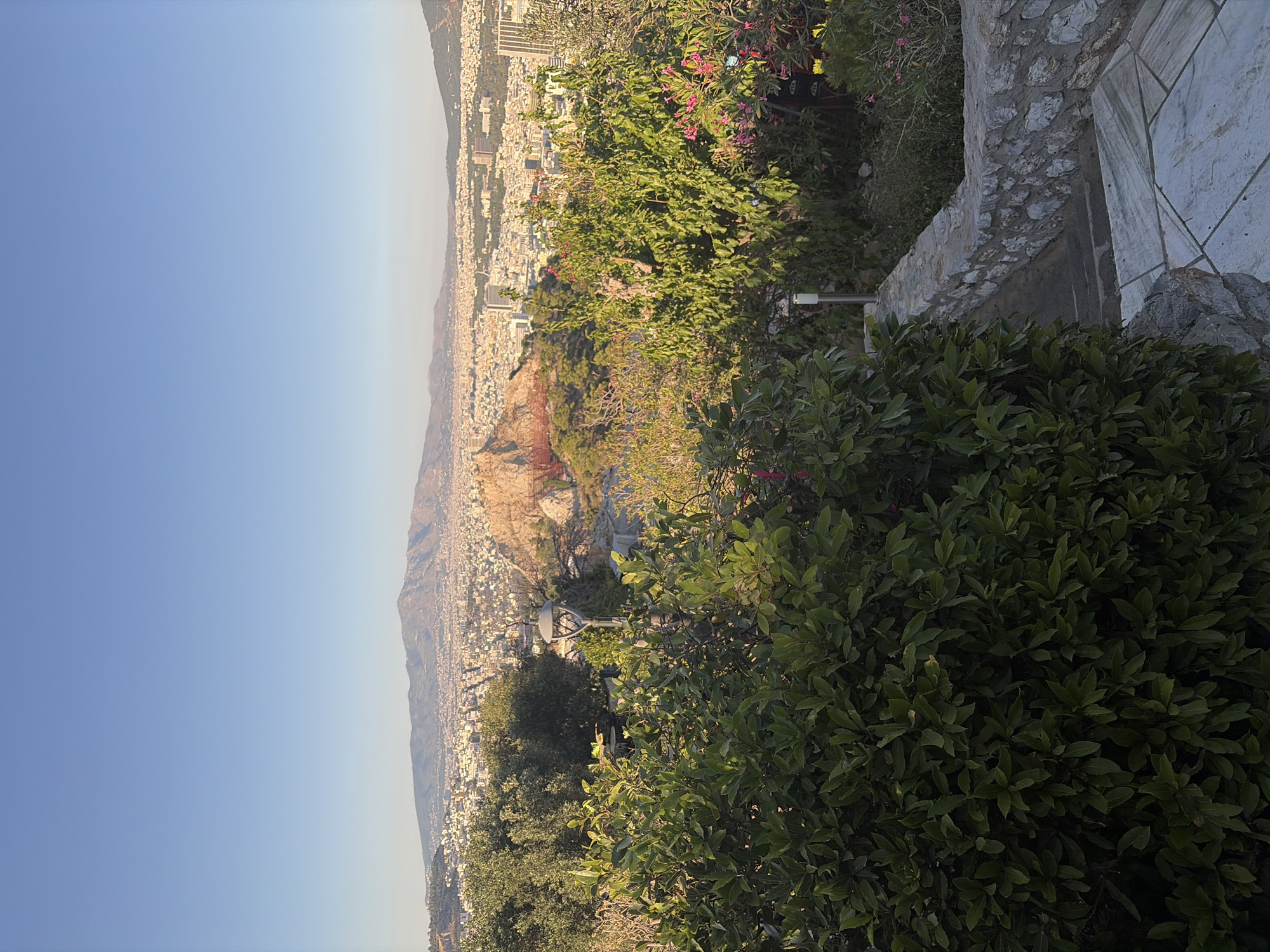 City overlook with rocky outcrops, forest paths, and live guitar