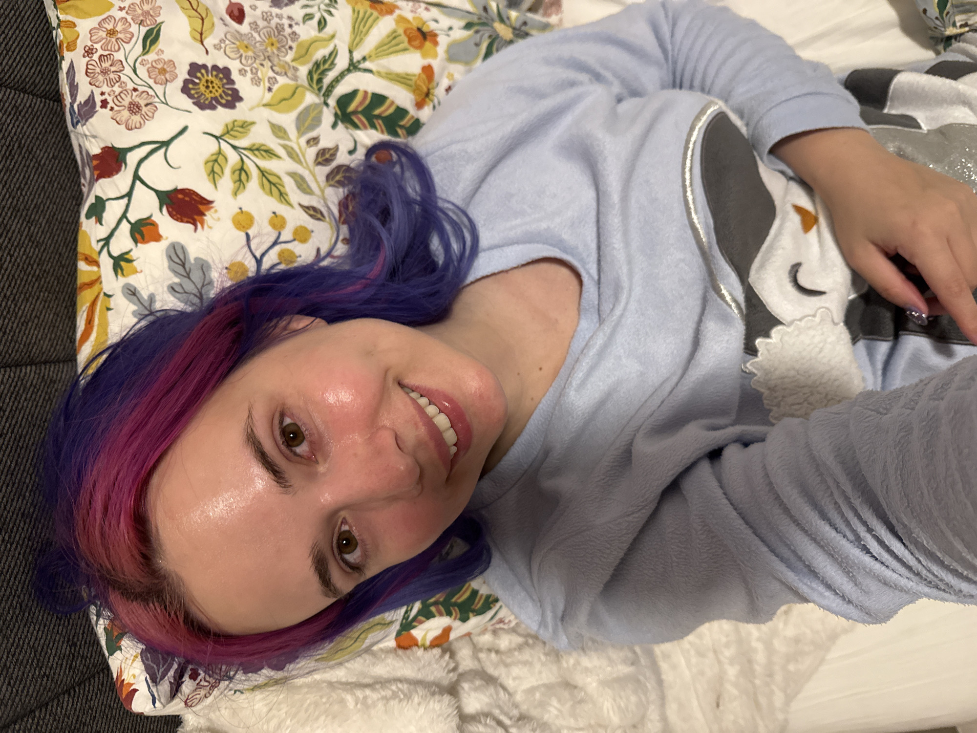 Woman with colorful hair rests in bed in Zagreb