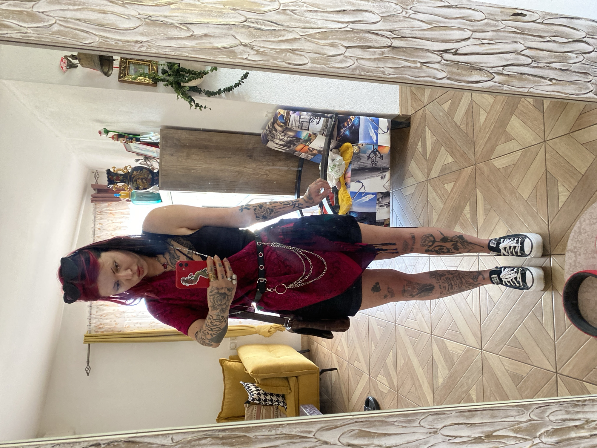 Woman takes indoor selfies with red smartphone, mirror reflections captured