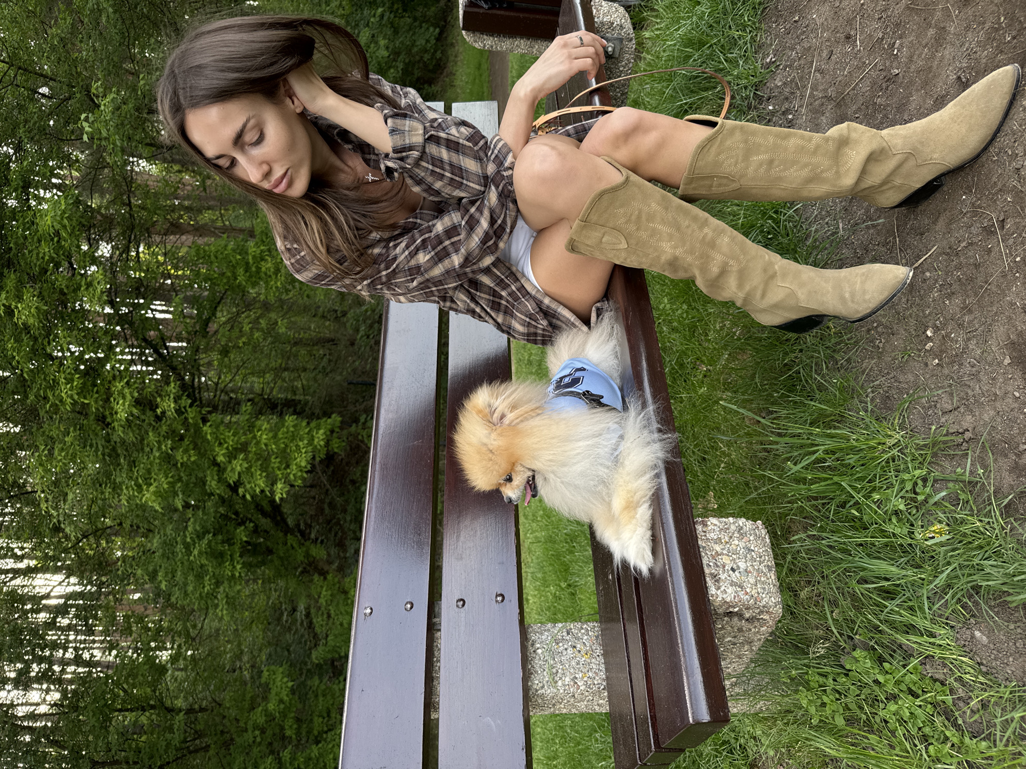 Woman and Pomeranian share quiet bench moment at park
