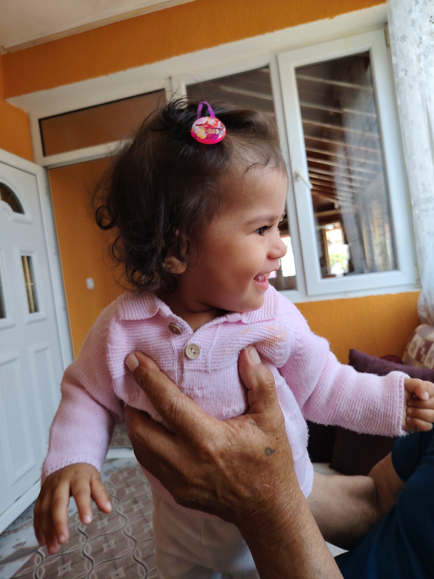 Toddler in pink cardigan held by adult in Byala Slatina