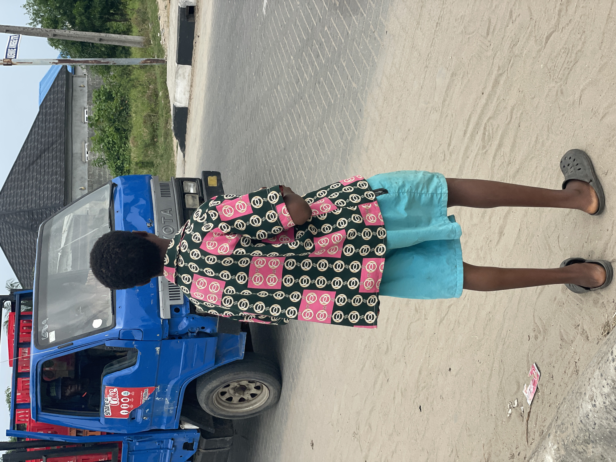 Young man stands by blue Toyota truck in Badagry