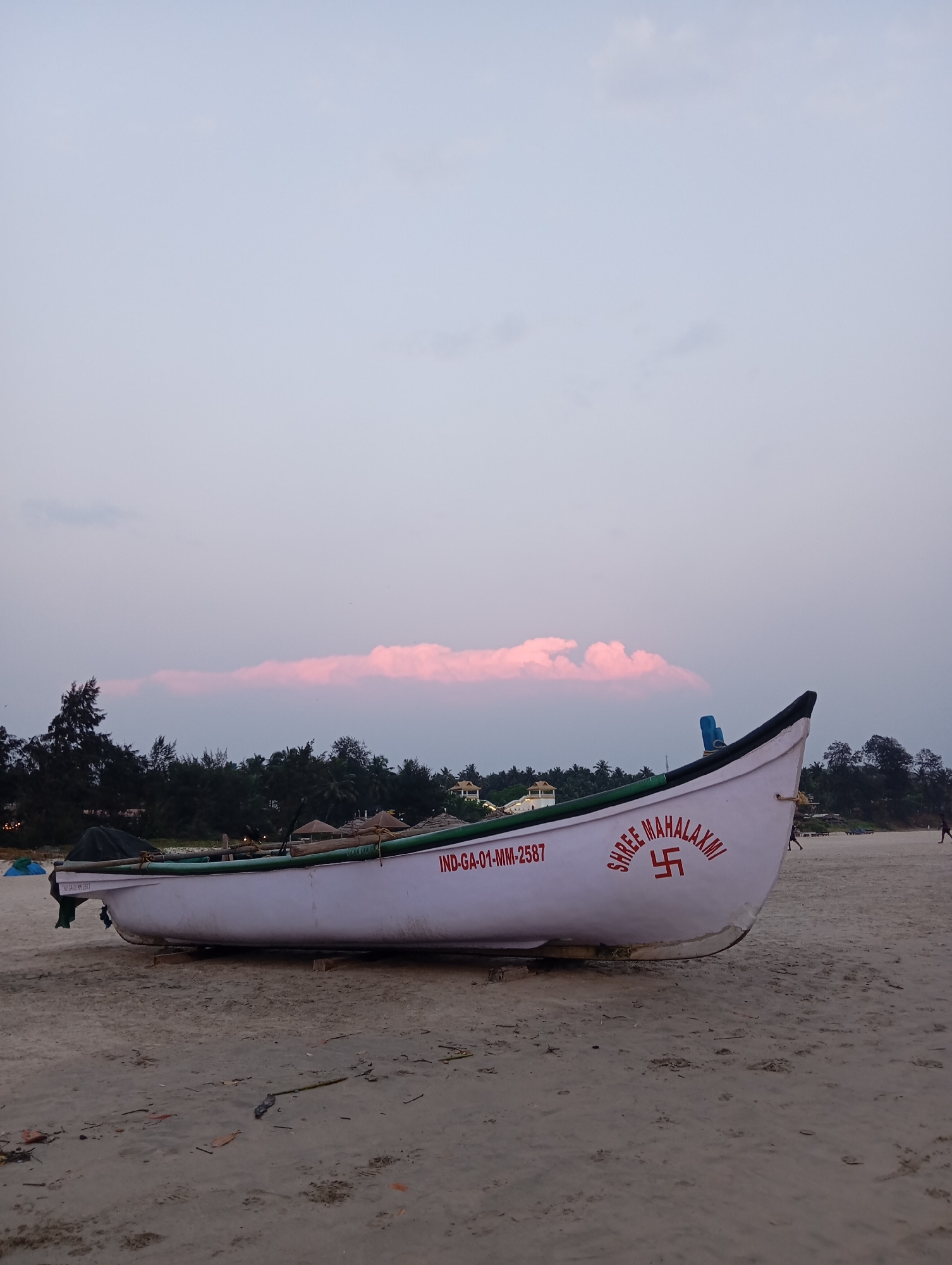 Fishing boat rests on Mandrem beach during sunset