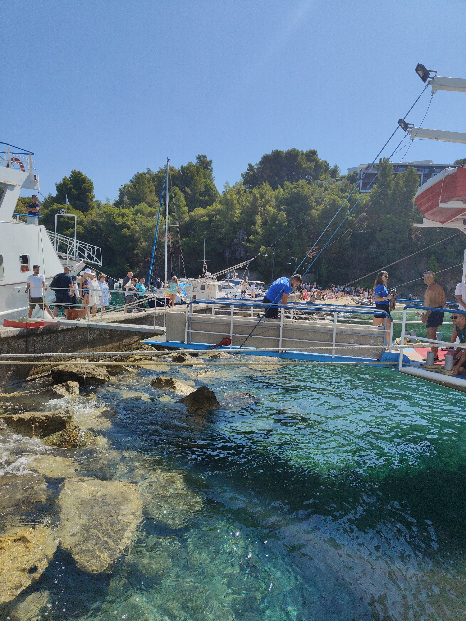 Passengers step off a white ferry onto a Greek stone pier