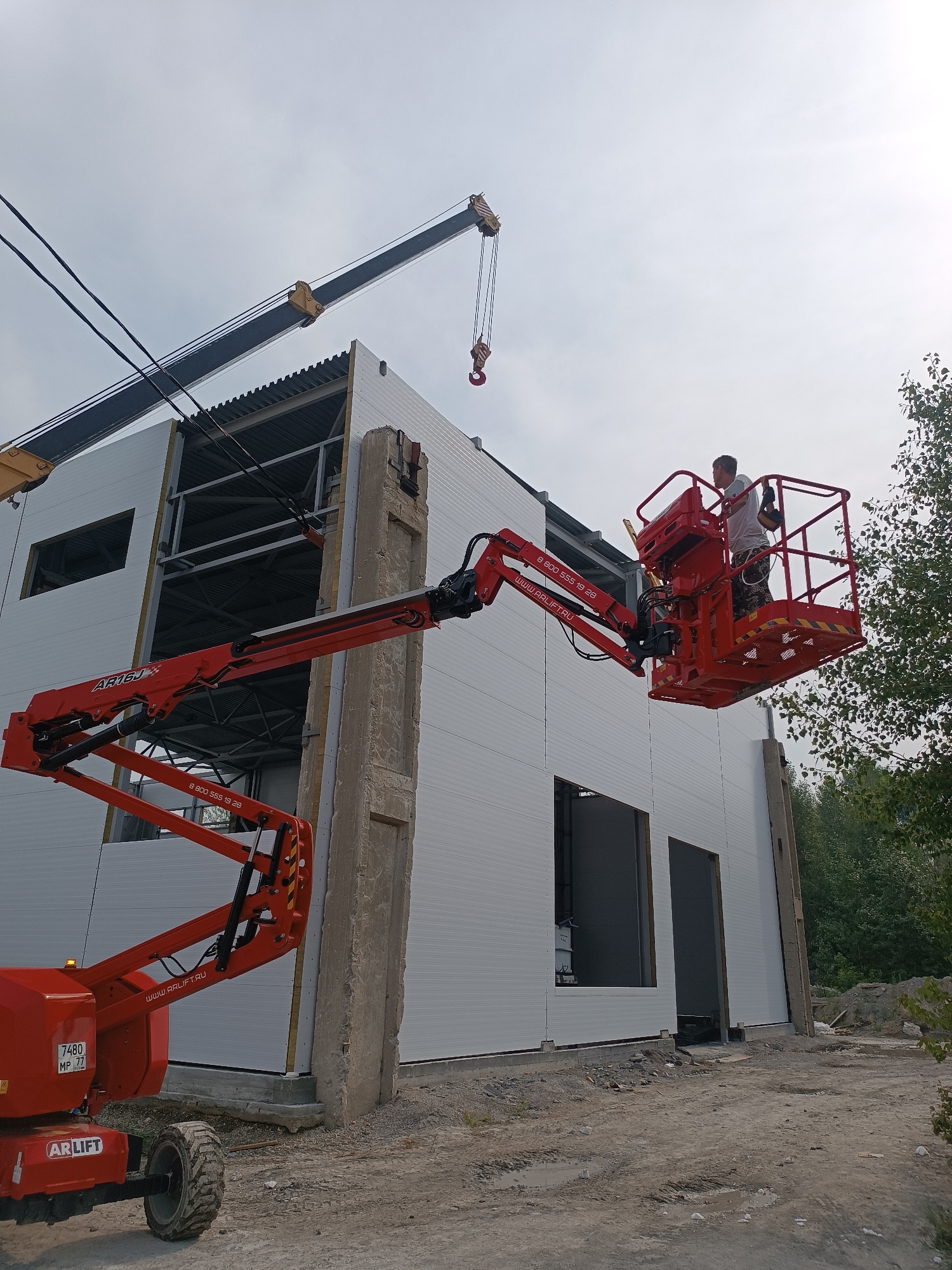 Crane and aerial lift crew work an industrial building exterior