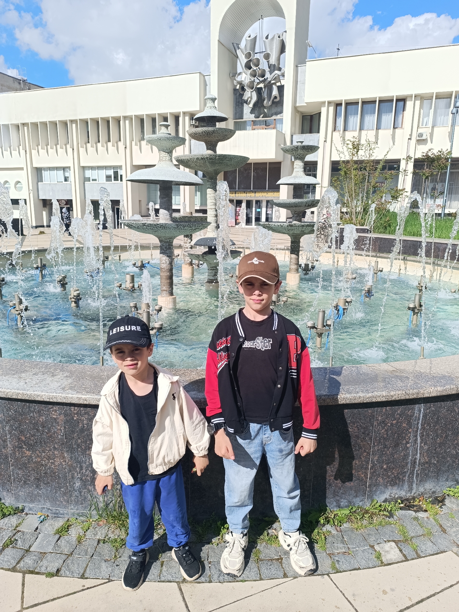 Two boys play at fountain and heart bench in Simferopol