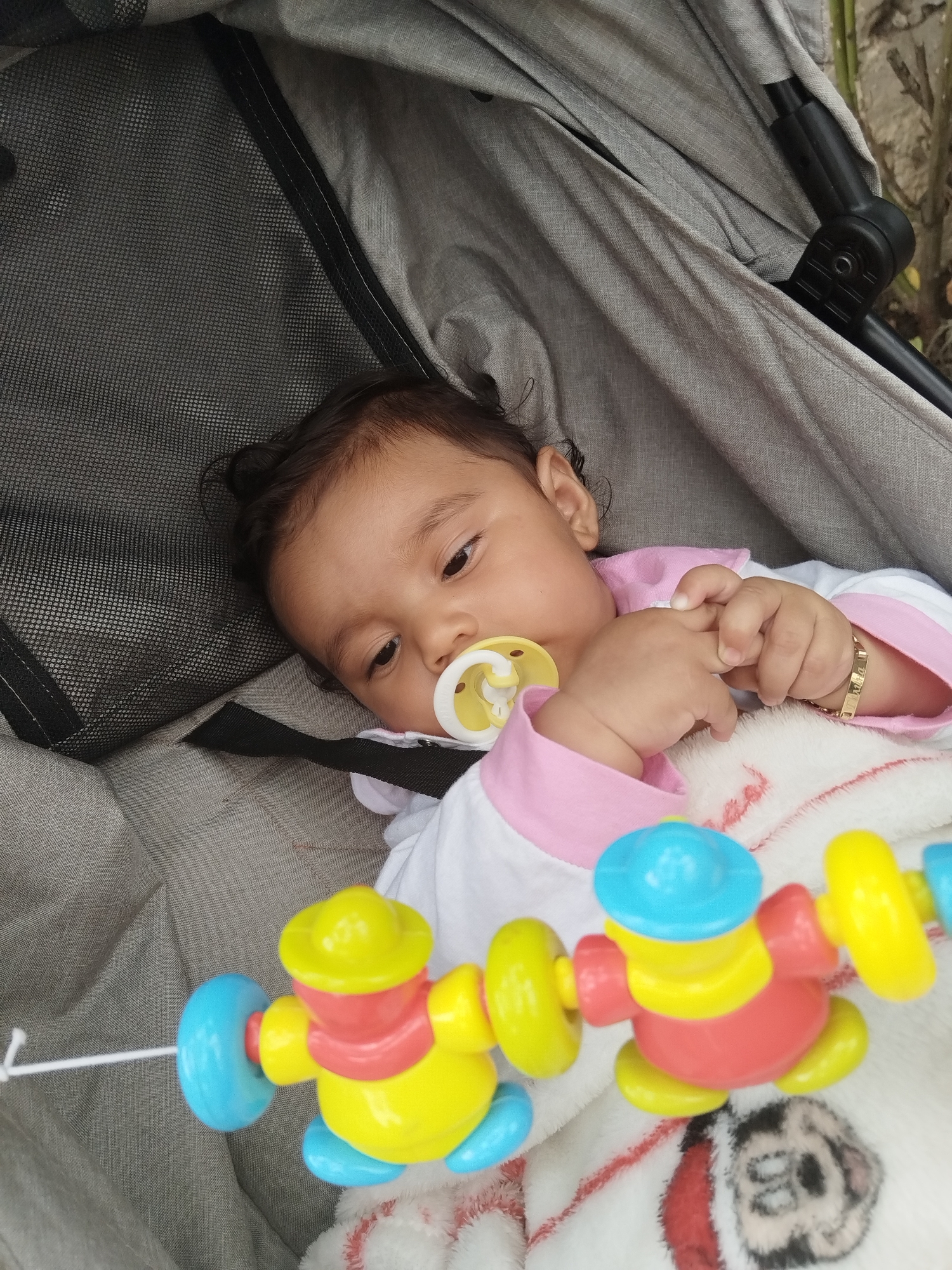 Baby rests peacefully in stroller with colorful pacifier
