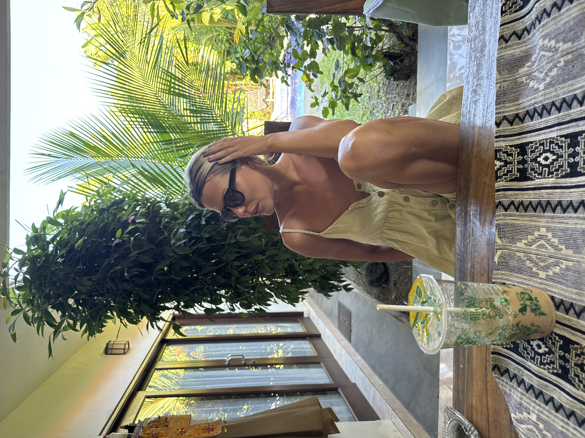 Woman enjoys morning smoke and drink on Kuta veranda