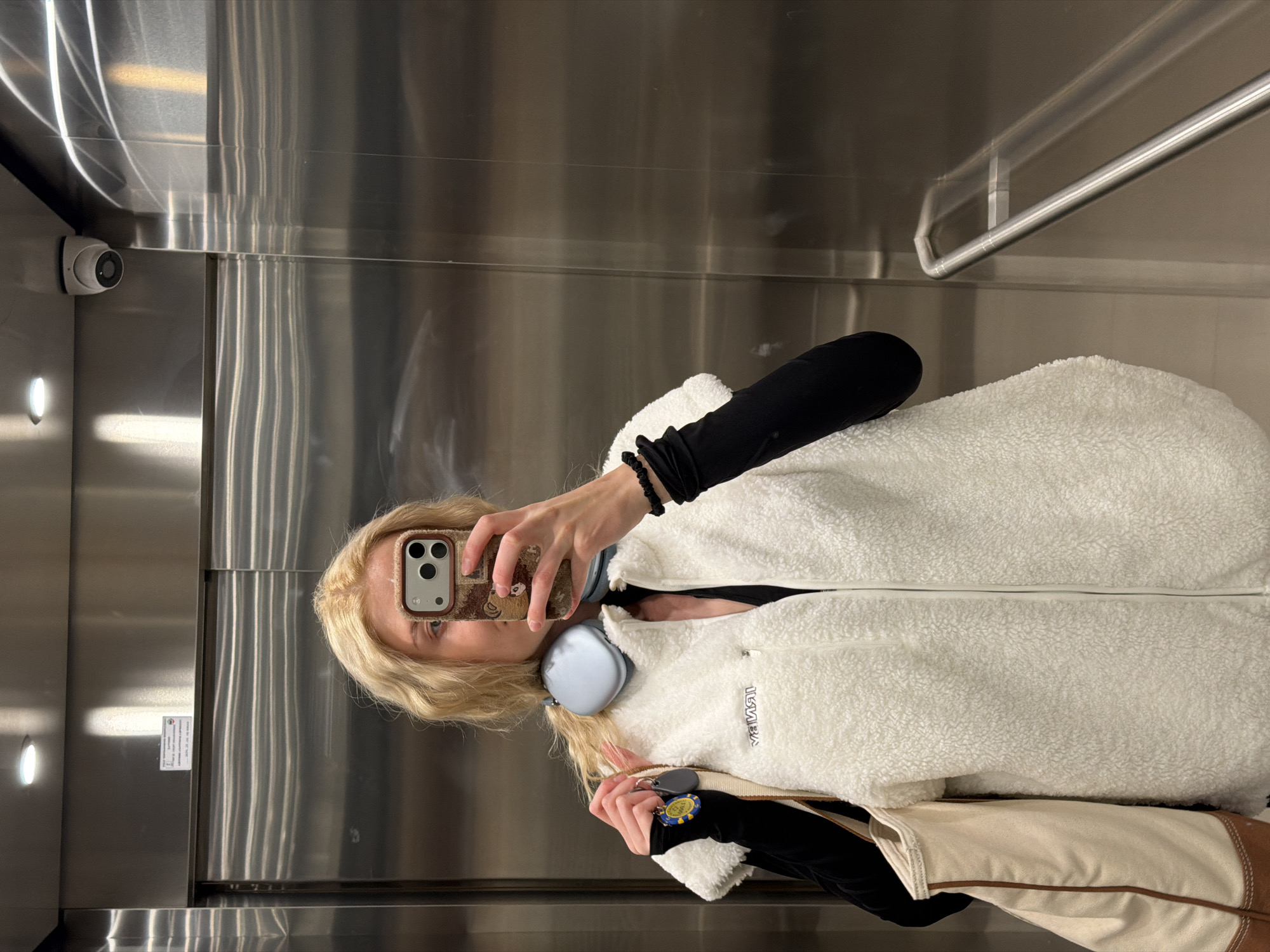 Woman takes elevator selfie in Belgrade wearing white jacket
