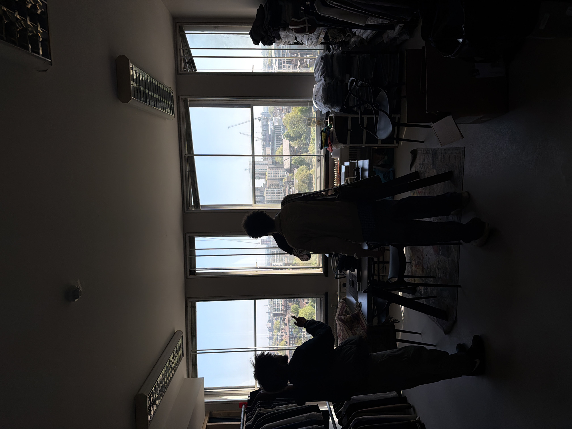 Two people silhouetted against London cityscape windows in daylit room