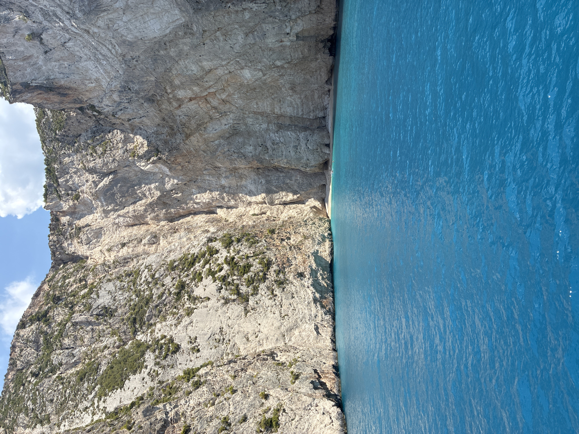 Rocky cliffs rise from turquoise water off the Greek coast