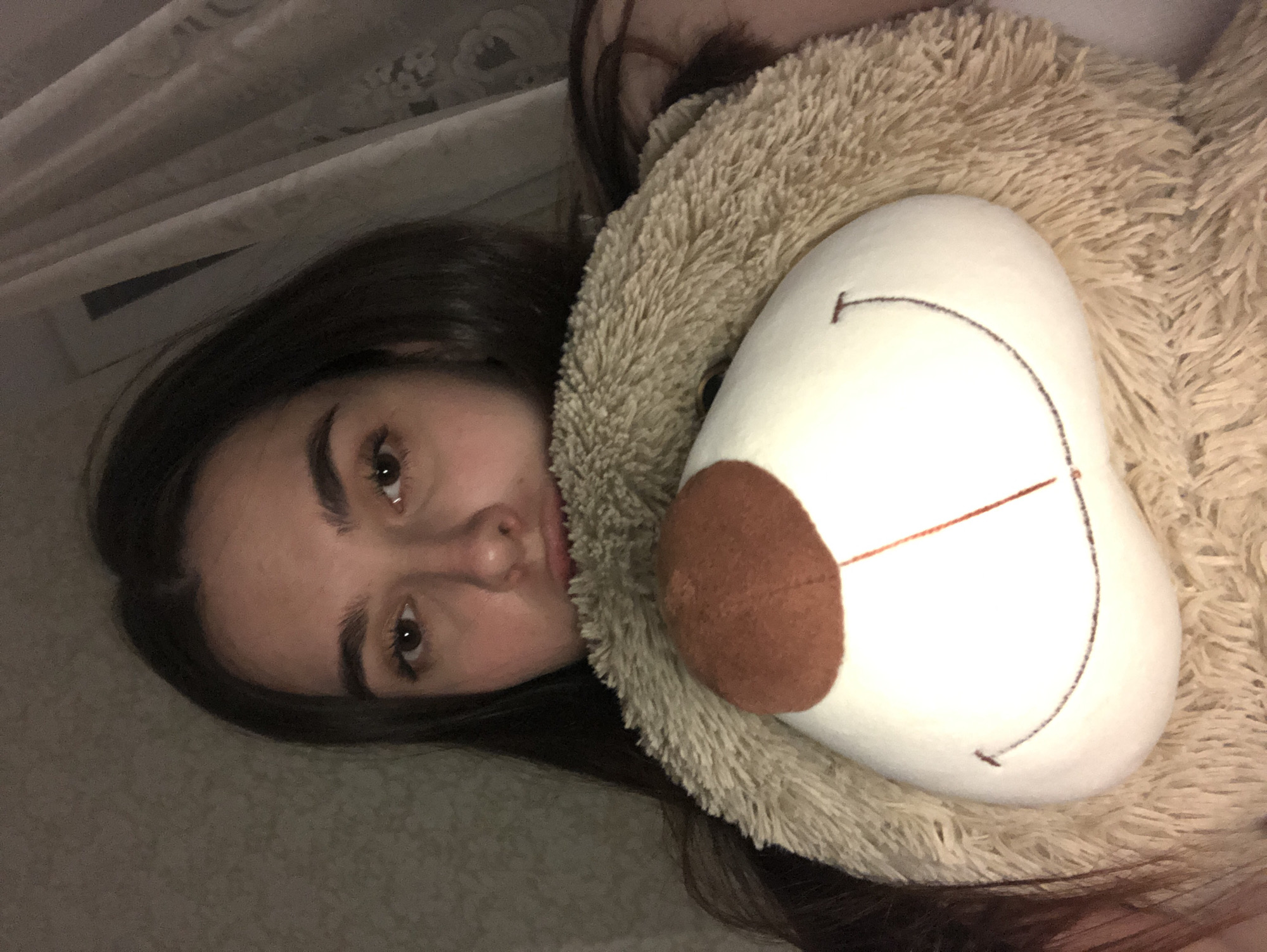Woman rests with teddy bear in Noviy bedroom