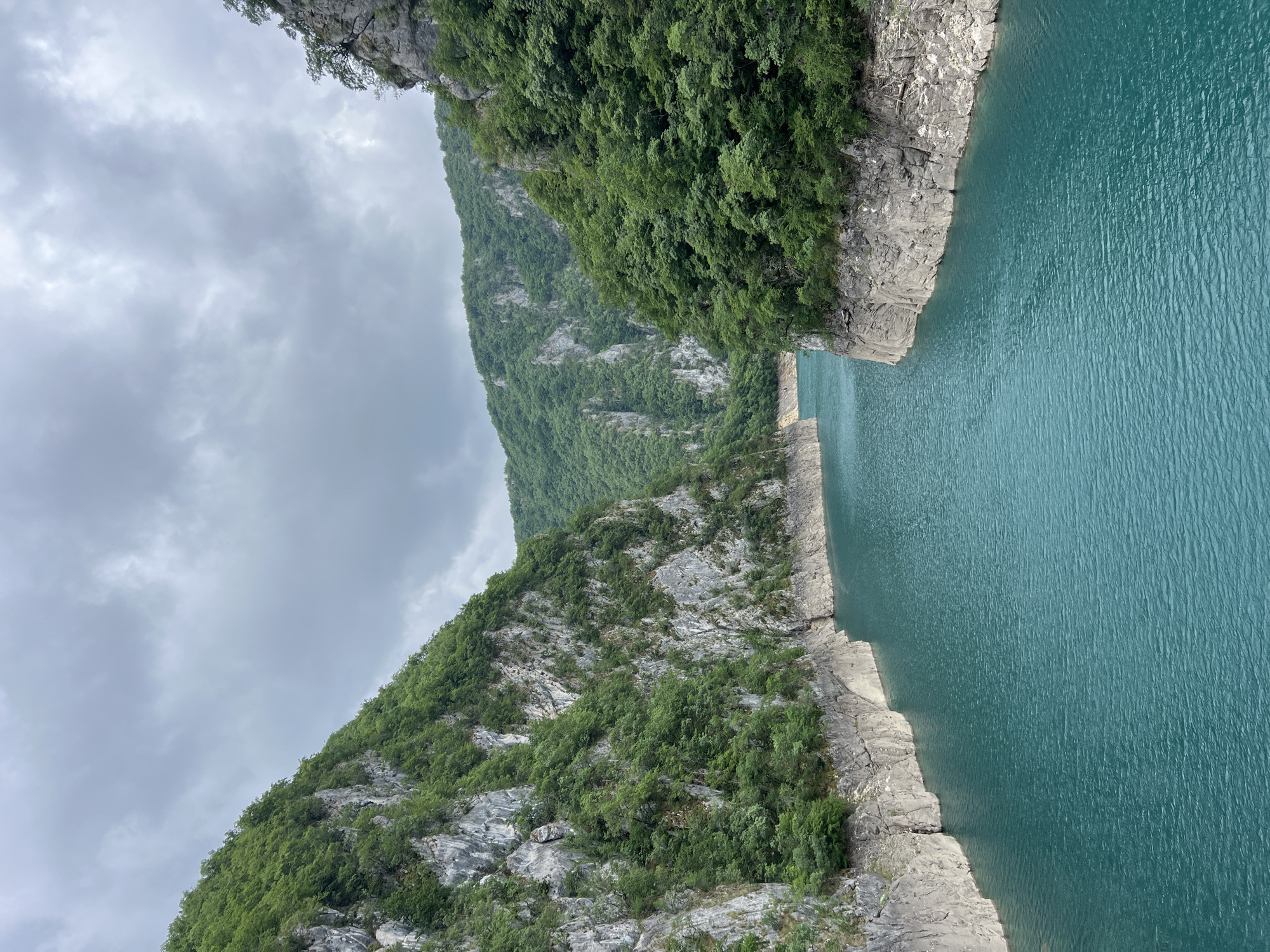 Person observes turquoise gorge waters from Montenegro mountain pathway
