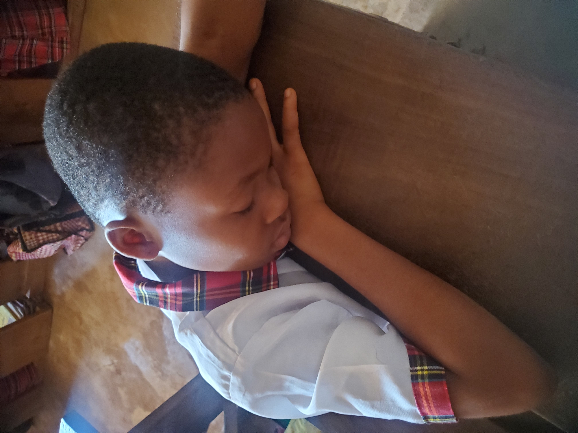 Student sleeps at desk during class in Nigerian school