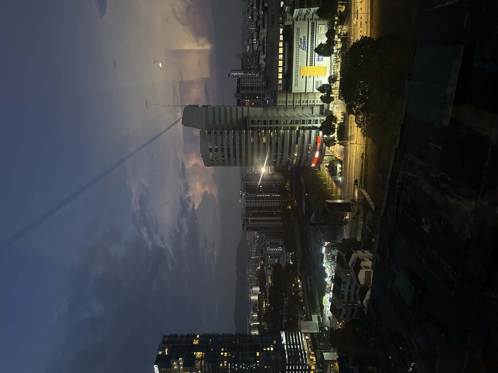 KL skyline at night, storm on the horizon, highway below