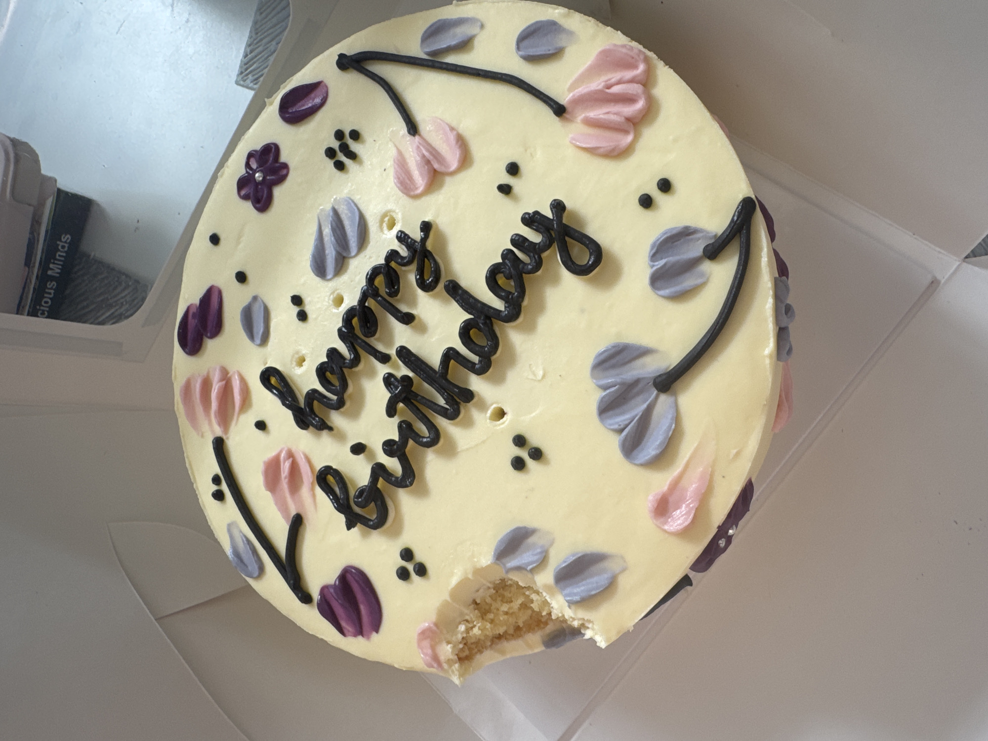Decorated birthday cake with yellow frosting observed in box