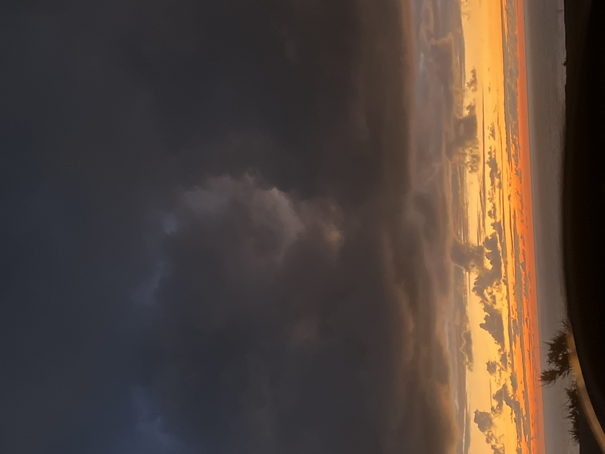 Dramatic storm clouds contrast orange sky over Ahrara, Morocco