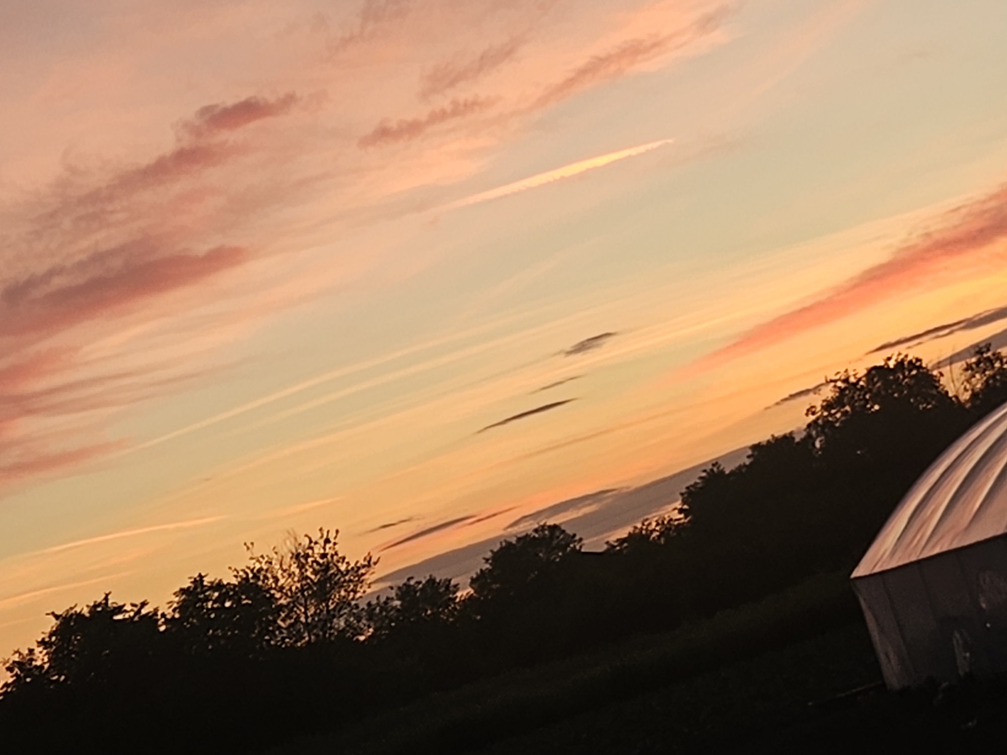 Rural sunset observed with colorful clouds over greenhouse landscape