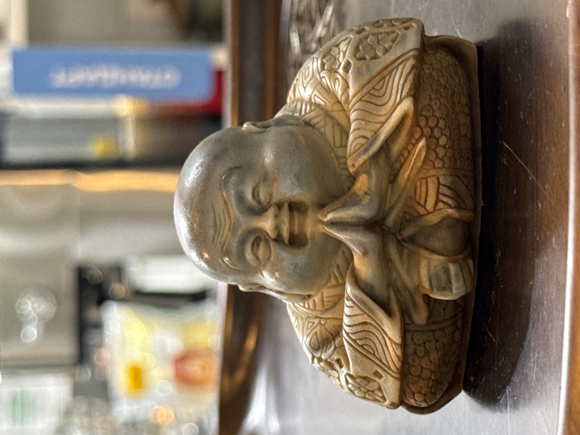 Smiling Buddha statue with carved robes on reflective surface