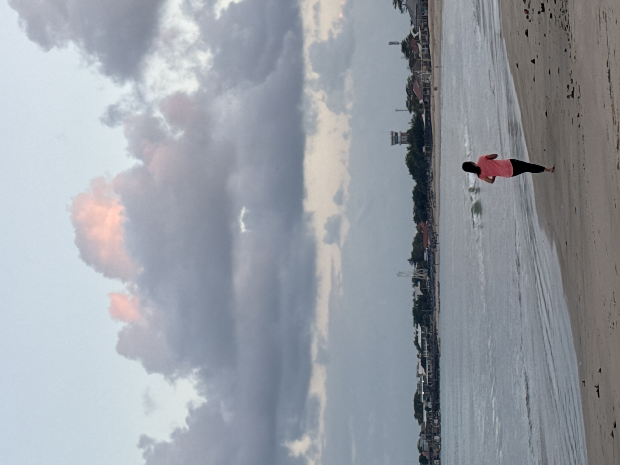 Kuta Beach at dusk: walkers, fishers, dogs, and dramatic clouds.