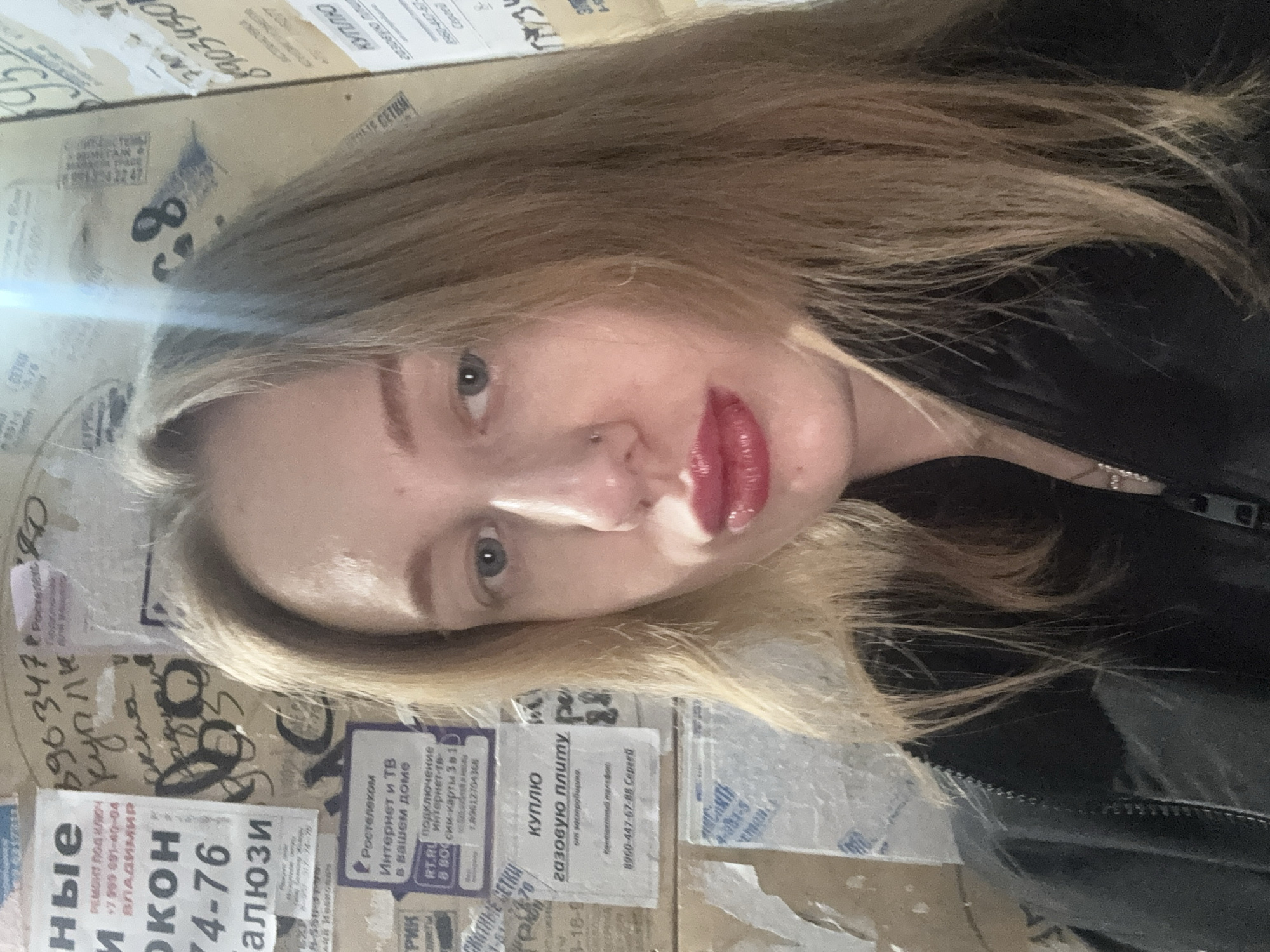 Woman takes selfies against advertisement wall in Kuleshovka