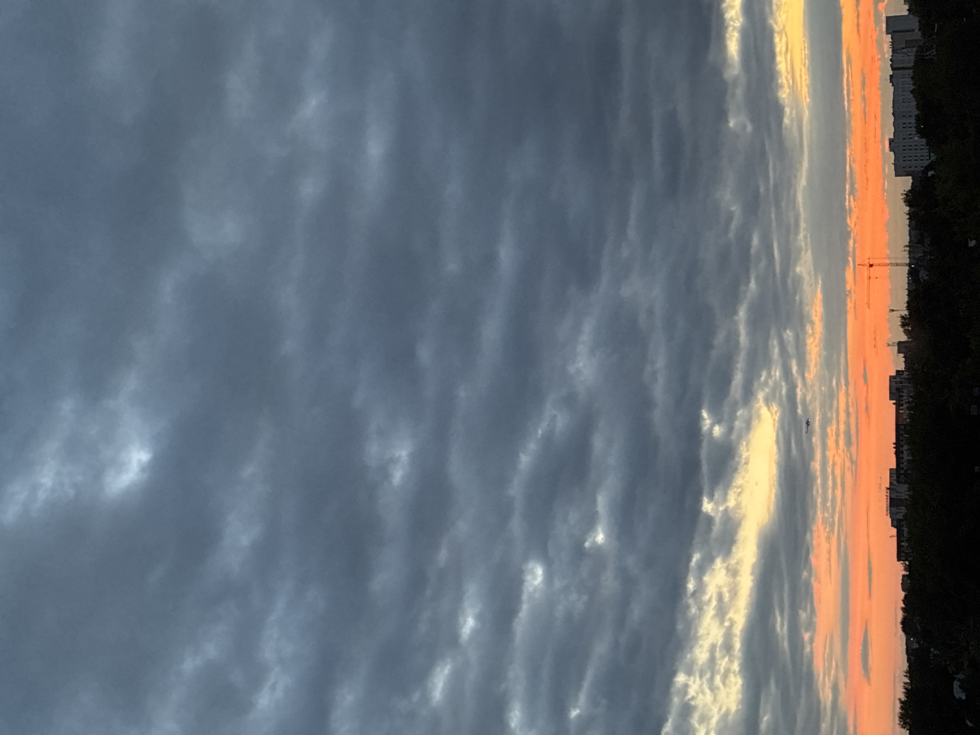 City skyline at sunset with a helicopter crossing stormy skies