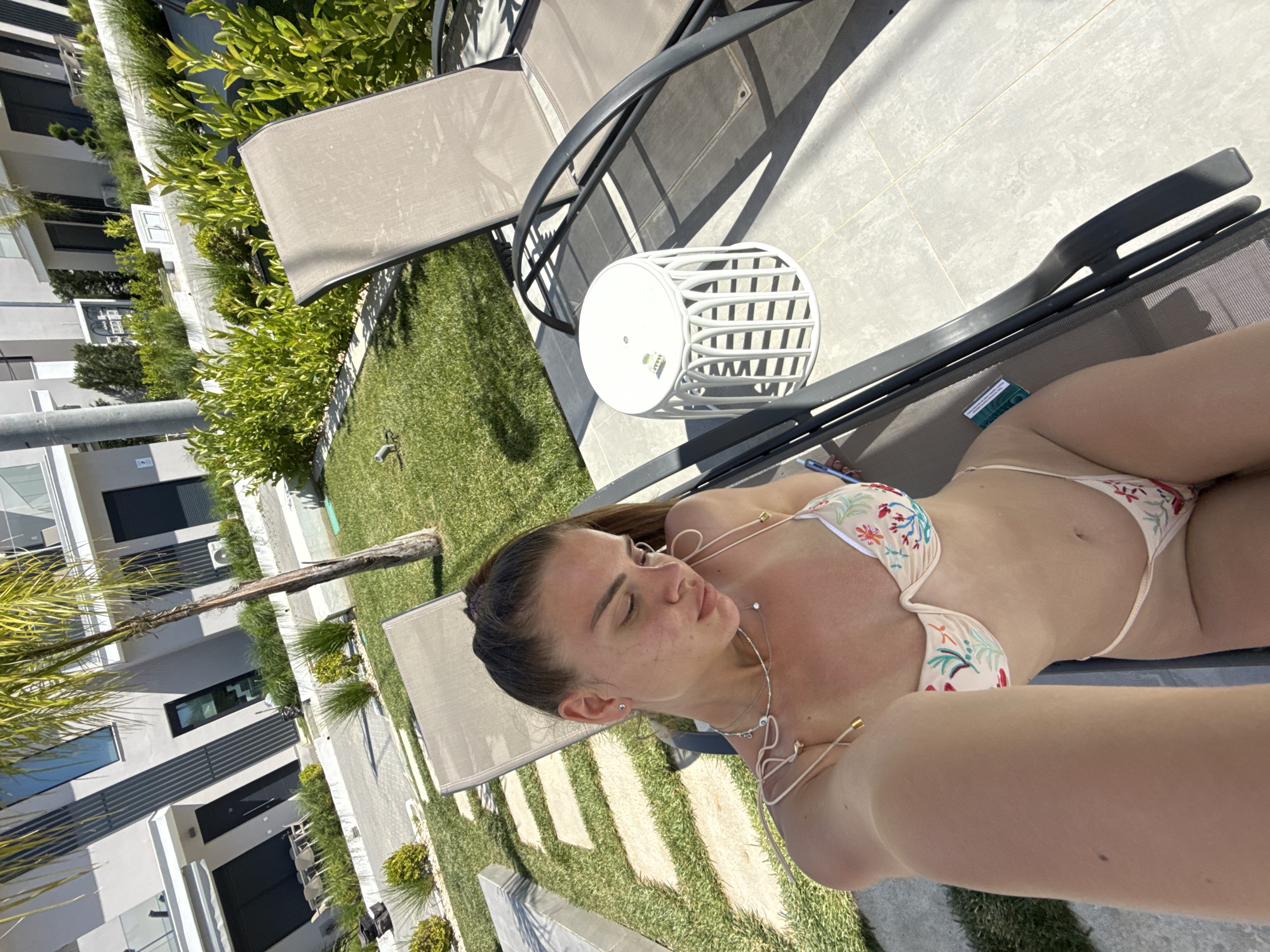 Woman captures outdoor selfies in bikini, beige top