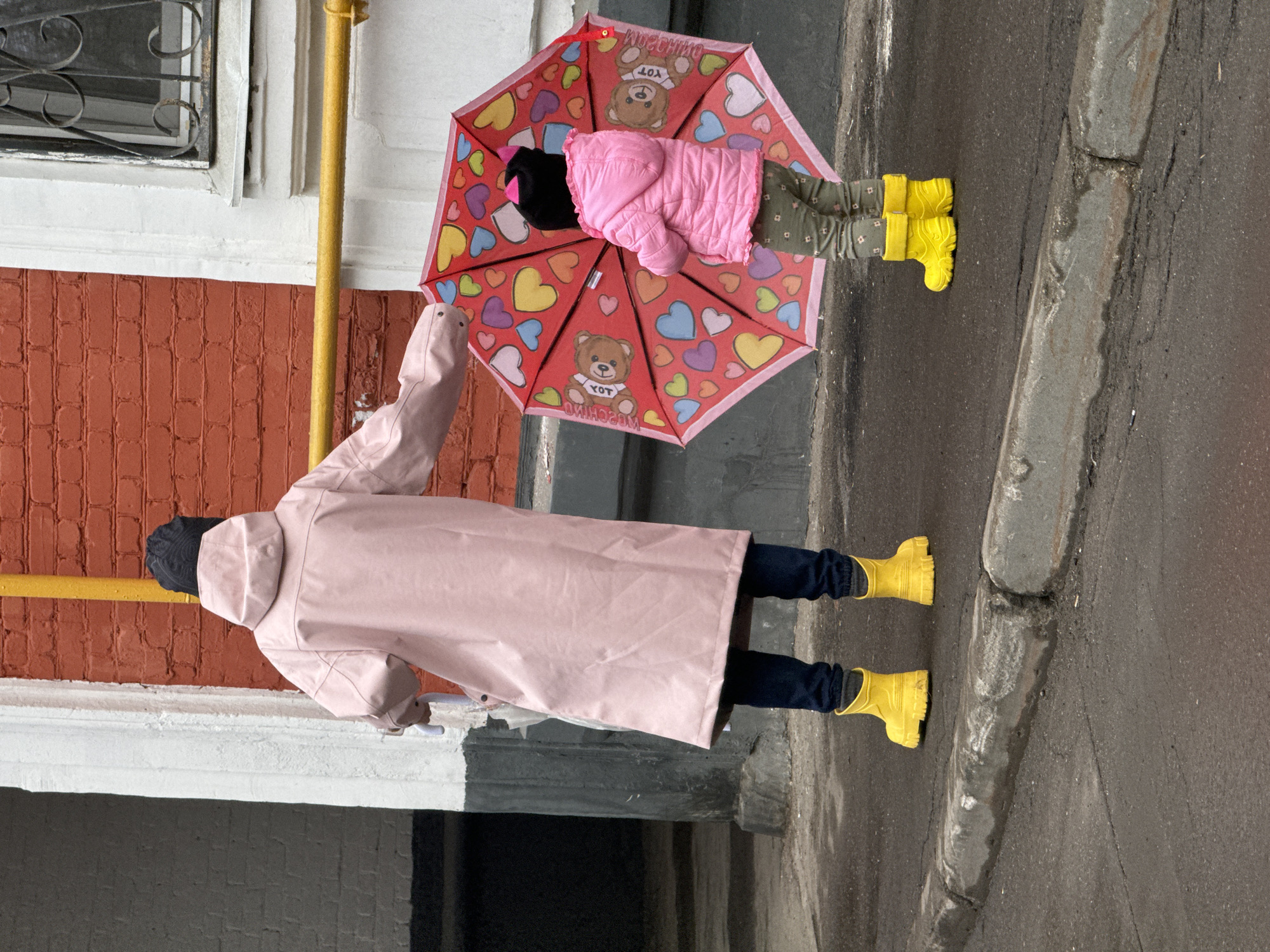 Children in colorful rain gear walk Moscow sidewalks