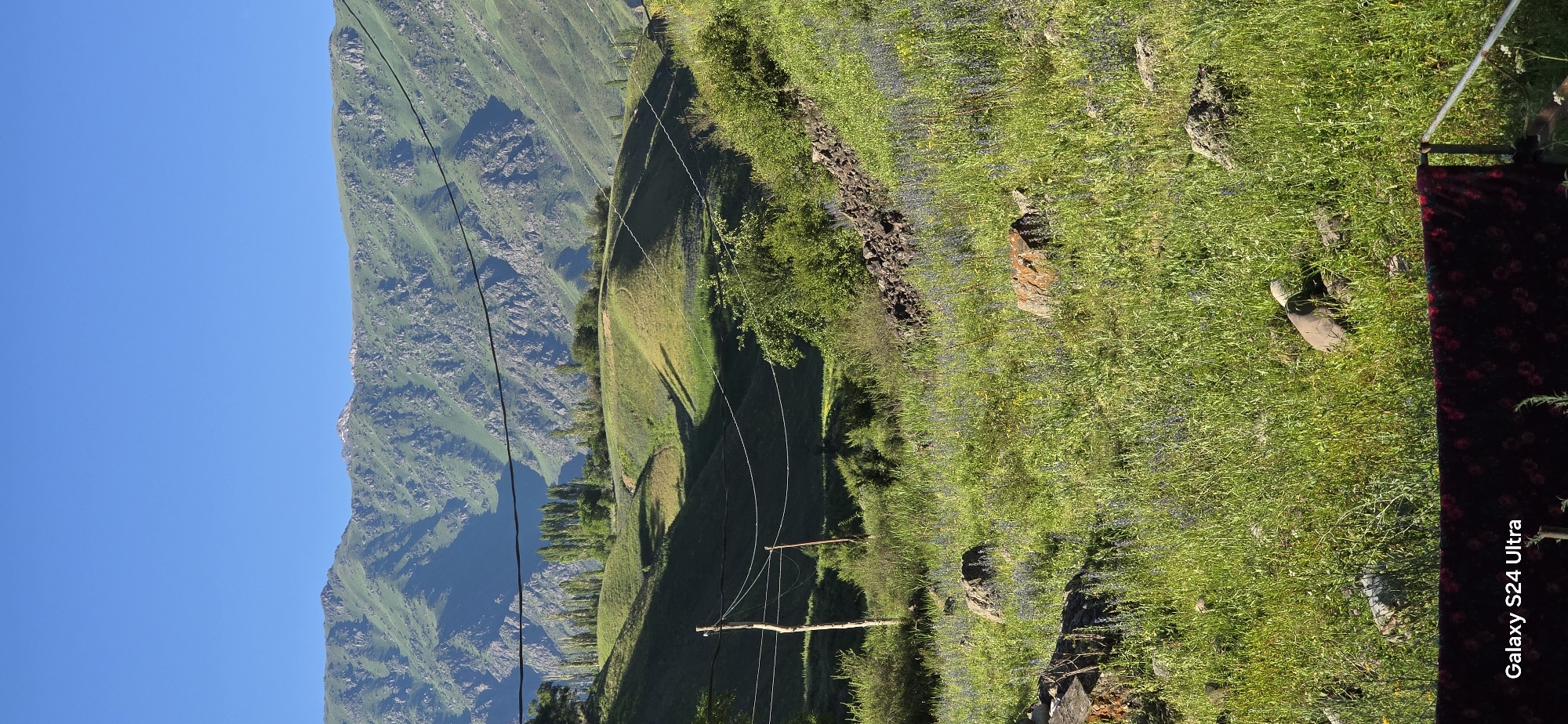 Sunny mountain slopes in Kyrgyzstan, moon visible in daylight