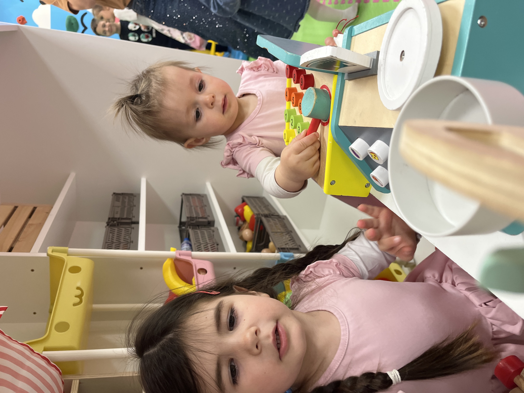 Young girls play with toy cash register in Sofia playroom