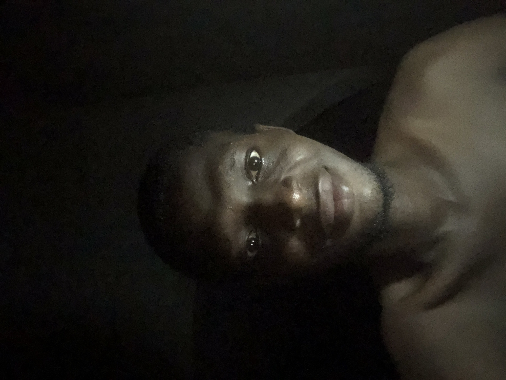 Rotated portrait of unidentified young man captured in dim lighting