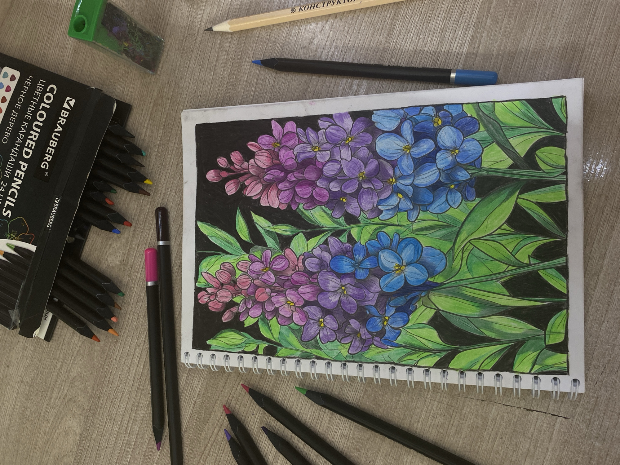 Artist sketches colorful flower stalks on wooden table surface