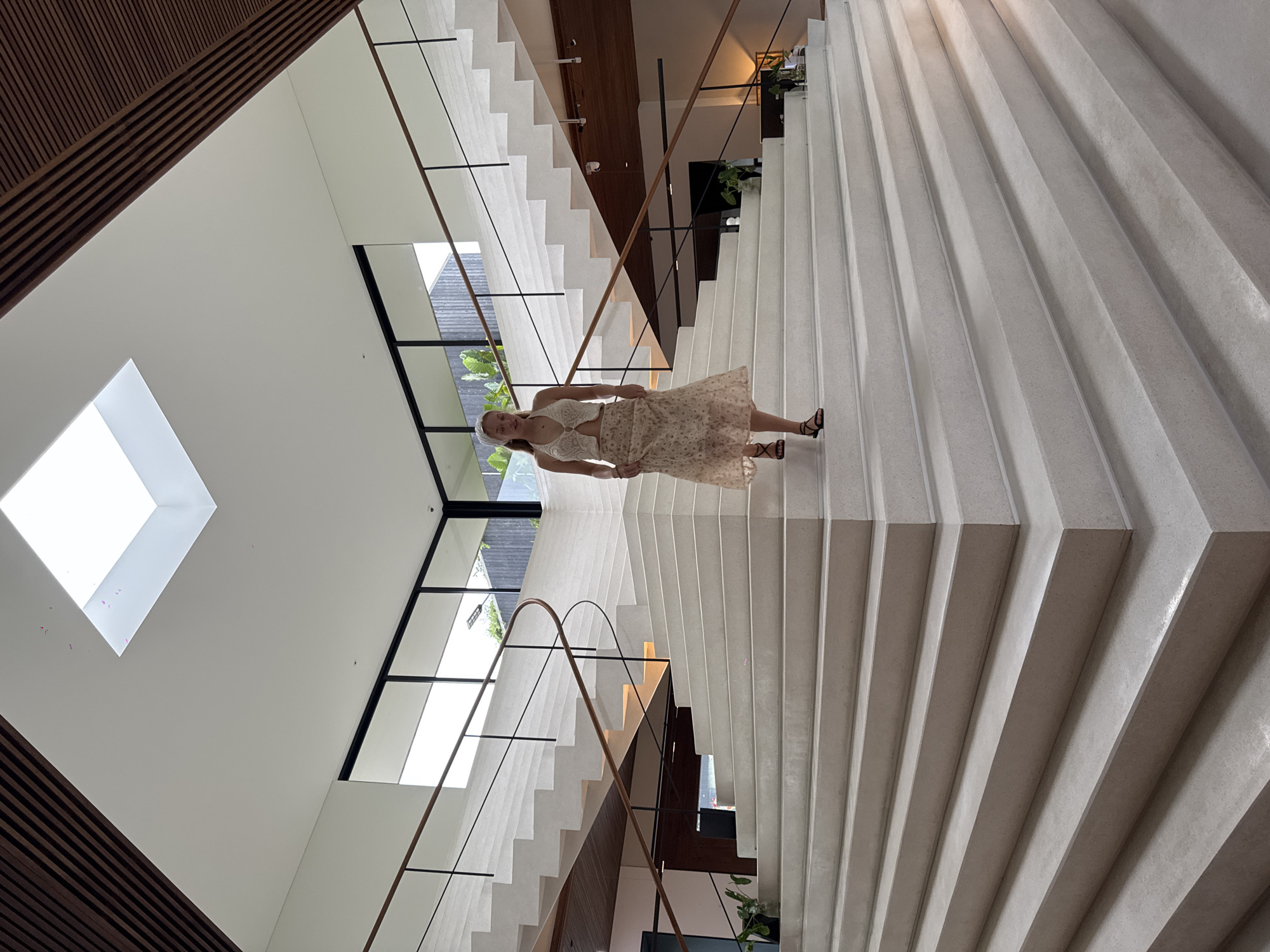 Woman walks modern split staircase in Si Sunthon building