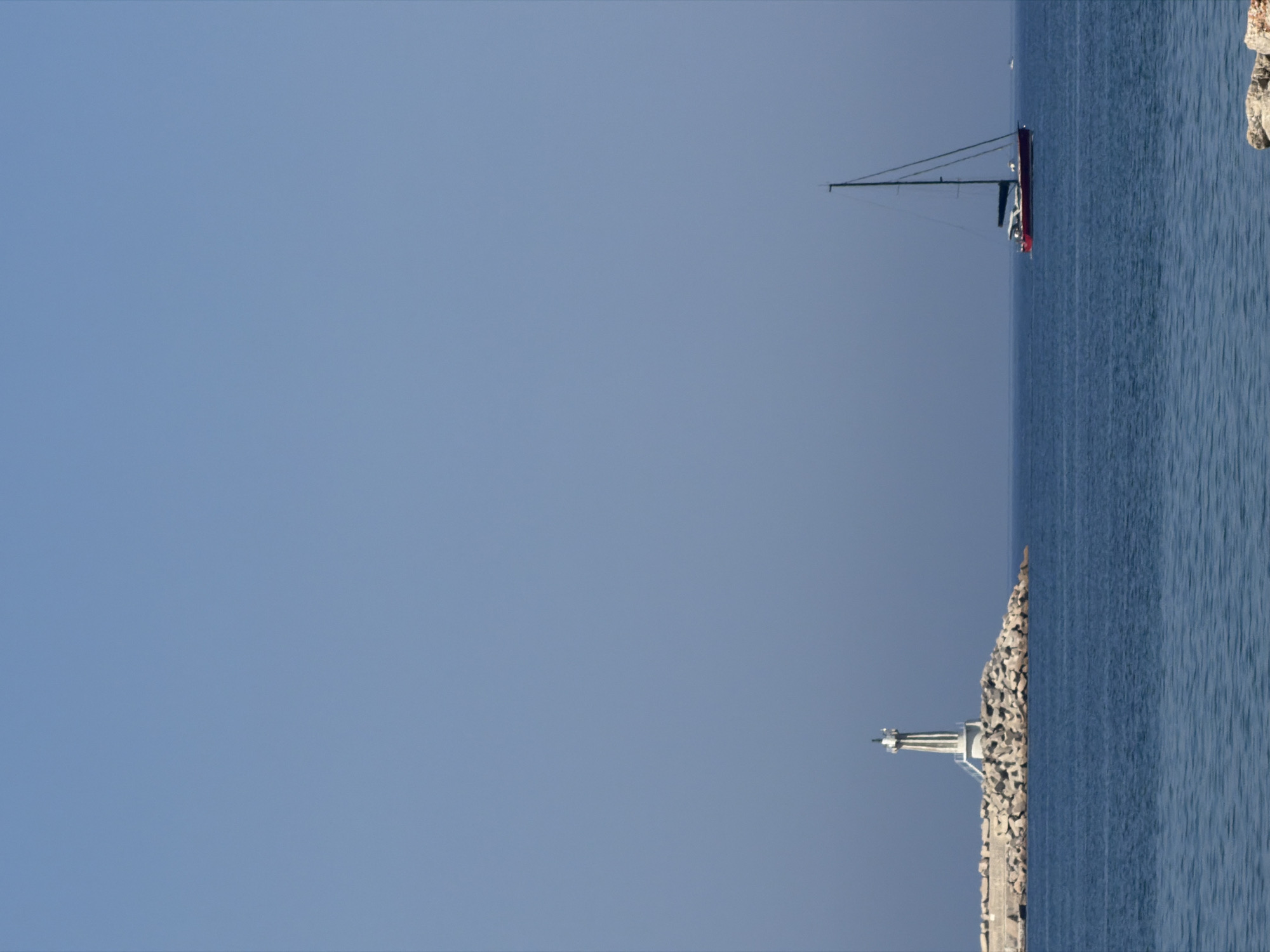 Lighthouse and sailboat on a calm breakwater in Bar, Montenegro