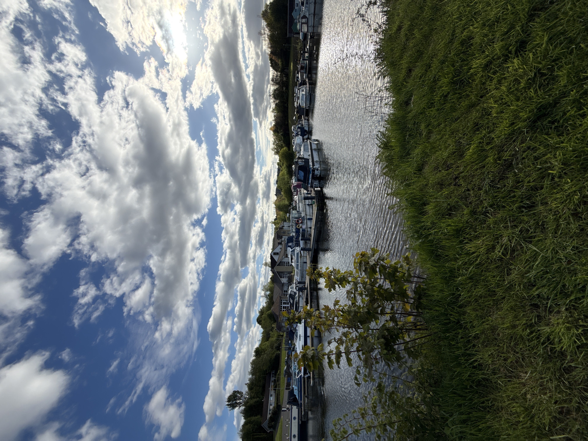 Cyclist adjusts fallen bicycle near canal with moored boats